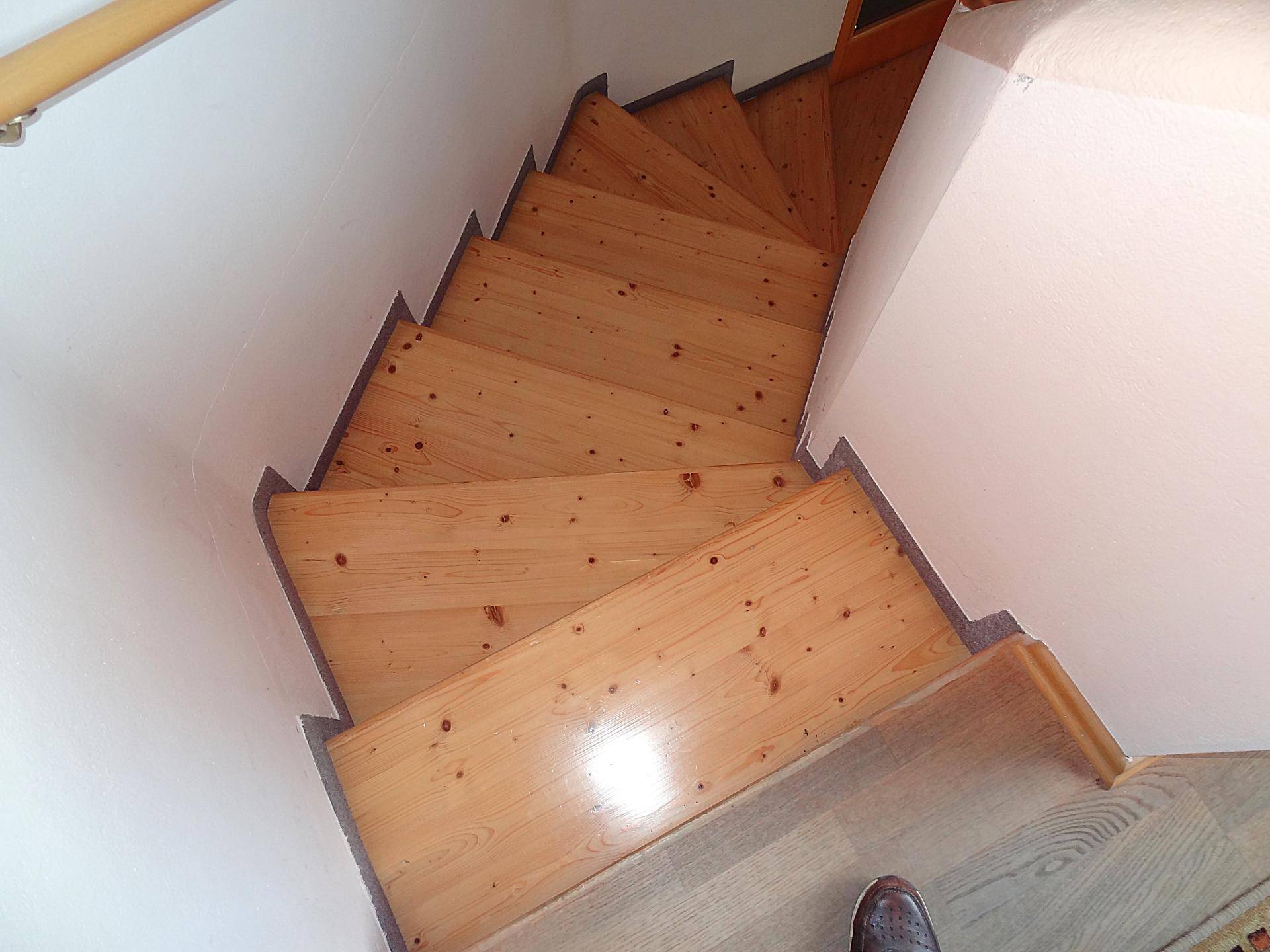 Holztreppe mit hellem Geländer, die in die obere Etage führt.