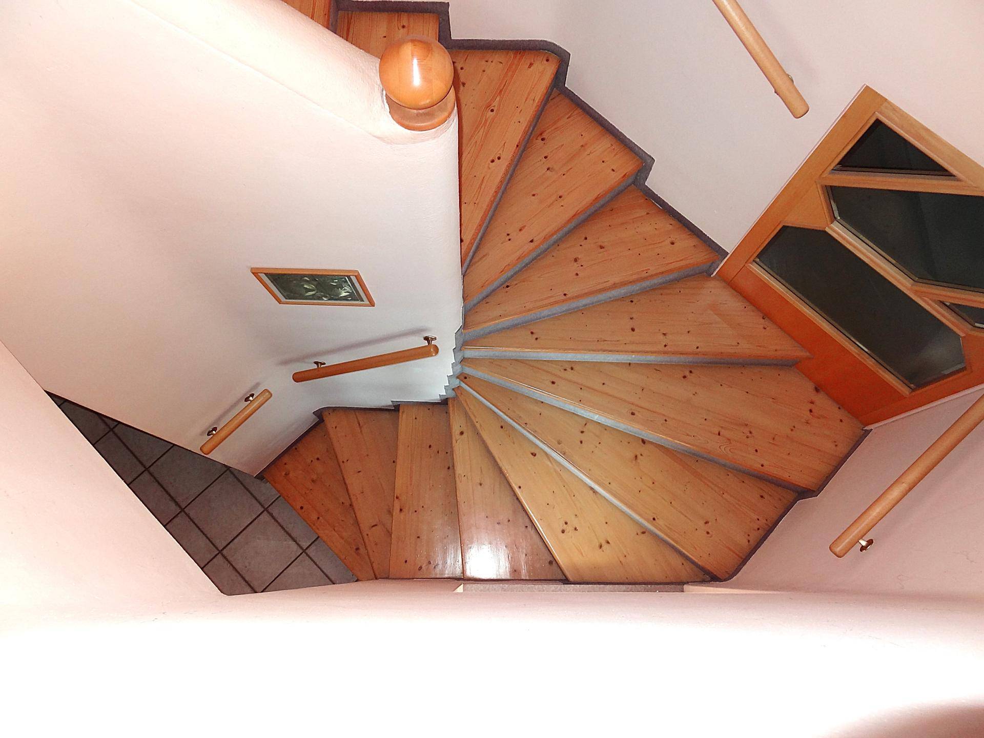Wendeltreppe aus Holz mit hellem Geländer, die verschiedene Ebenen verbindet.