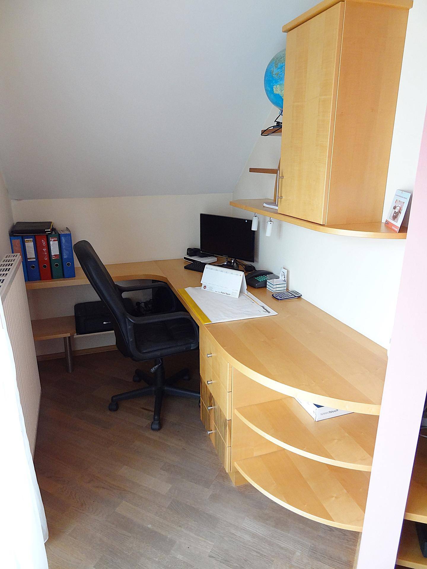 Helles Arbeitszimmer mit Holzschreibtisch und Dachschräge.