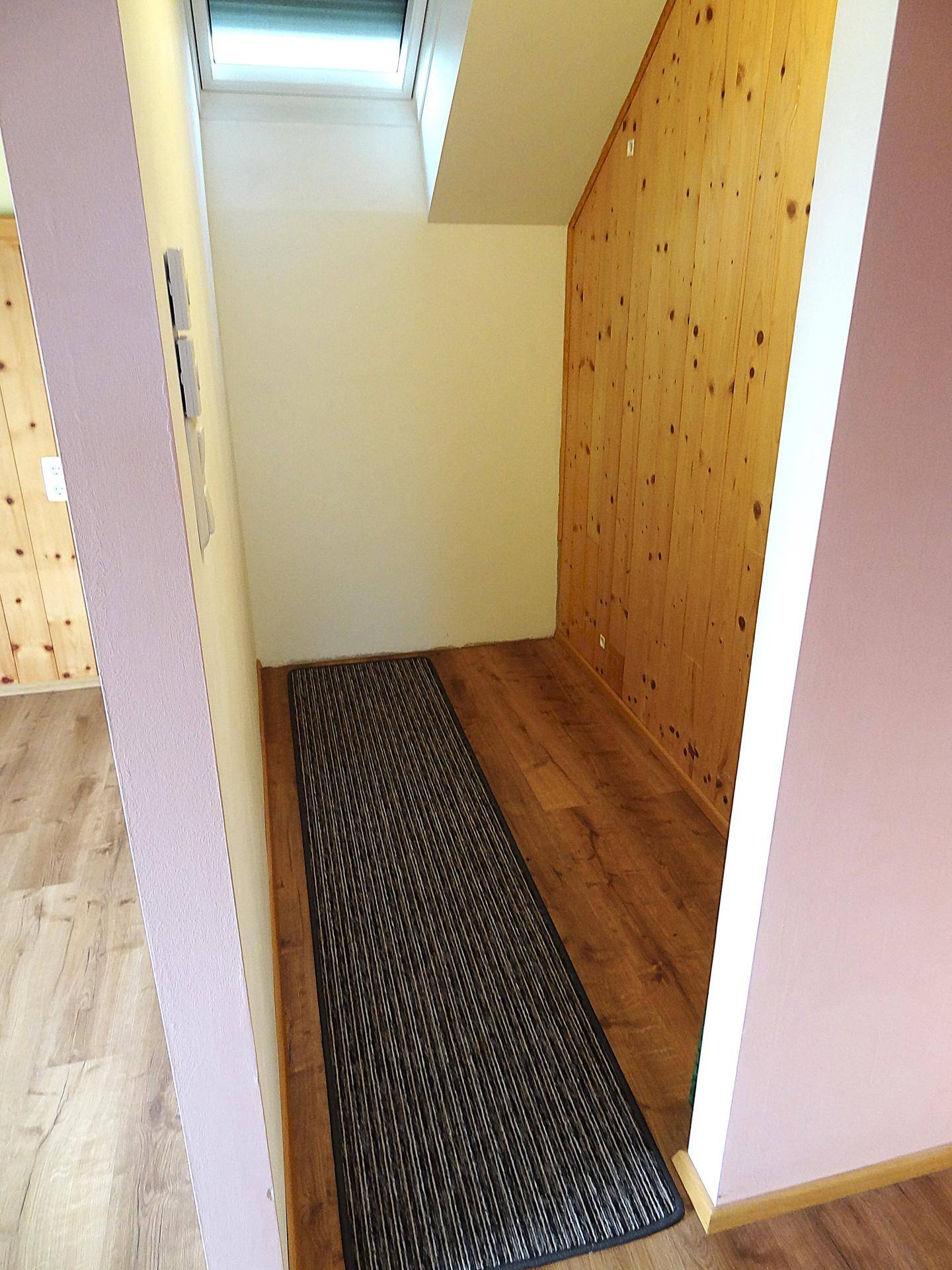 Flur mit Holzwandverkleidung, Laminatboden und Dachfenster.