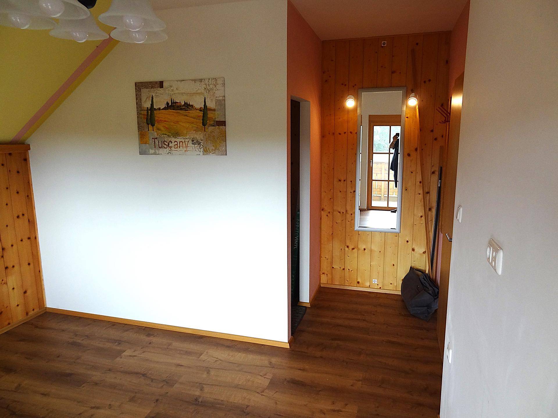 Flur mit Holzwandverkleidung, Spiegel und Laminatboden.