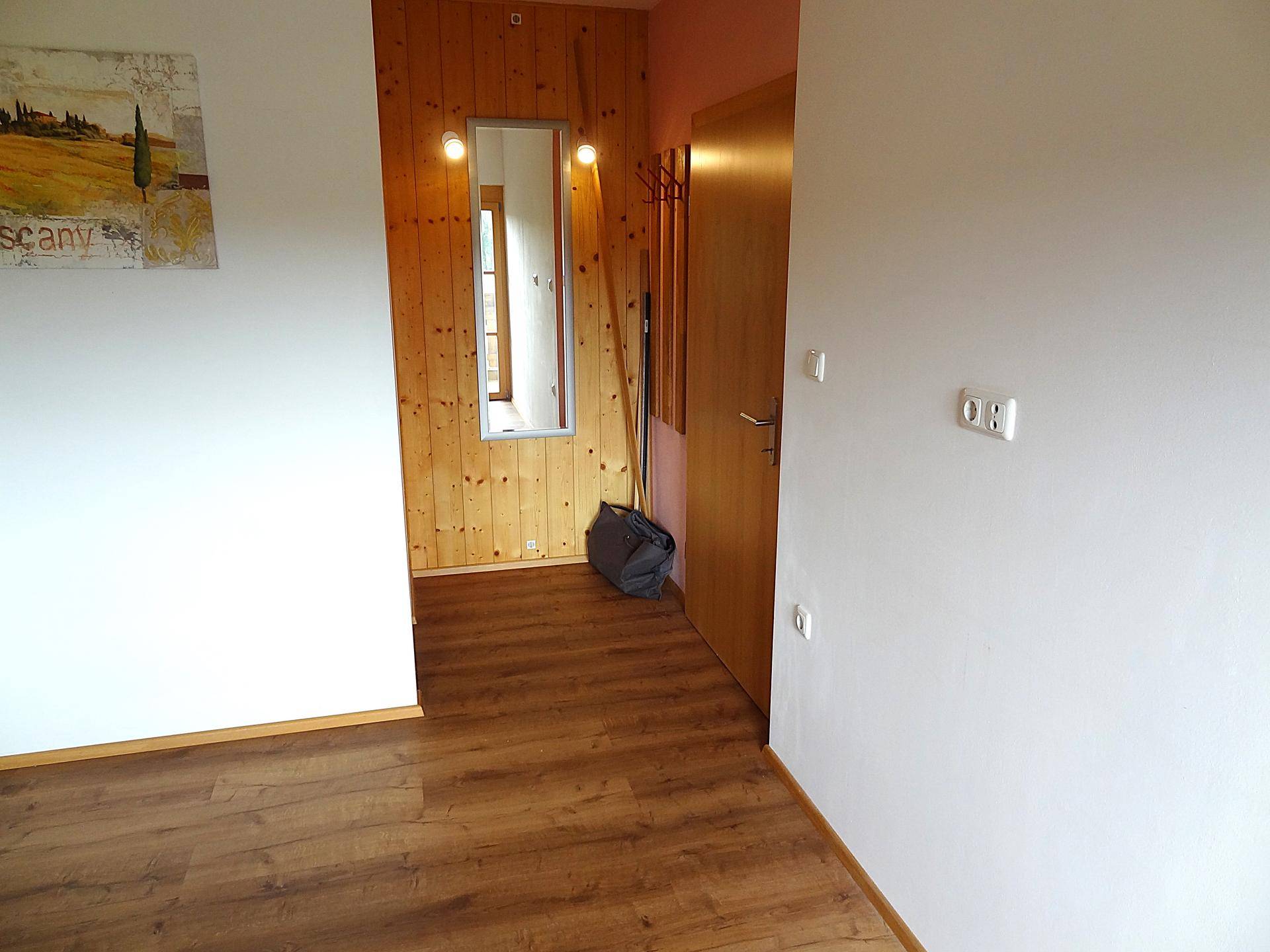 Flur mit Holzwandverkleidung, Spiegel und Laminatboden.