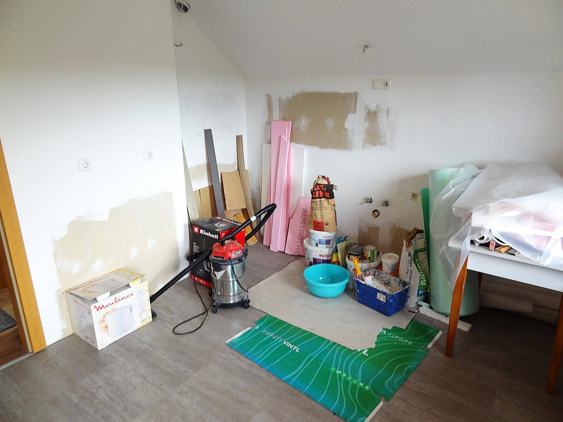 Raum in Renovierung mit Baumaterialien und unfertigen Wänden.