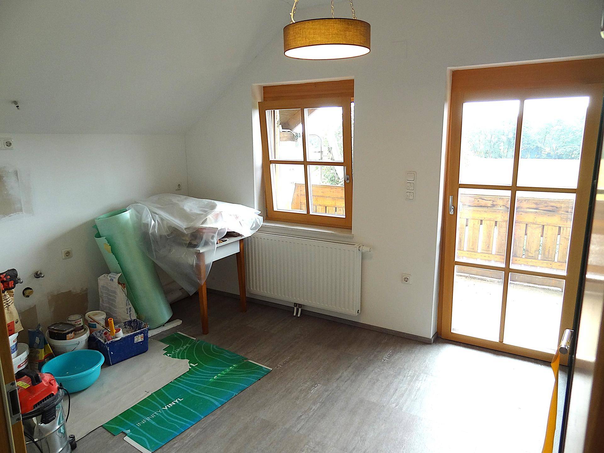 Raum in Renovierung mit Fenster, Balkontür und Baumaterialien.