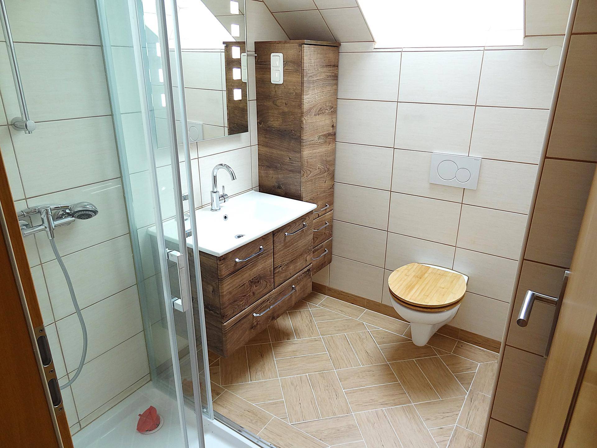 Modernes Badezimmer mit Dusche, Waschtisch und WC unter Dachschräge.
