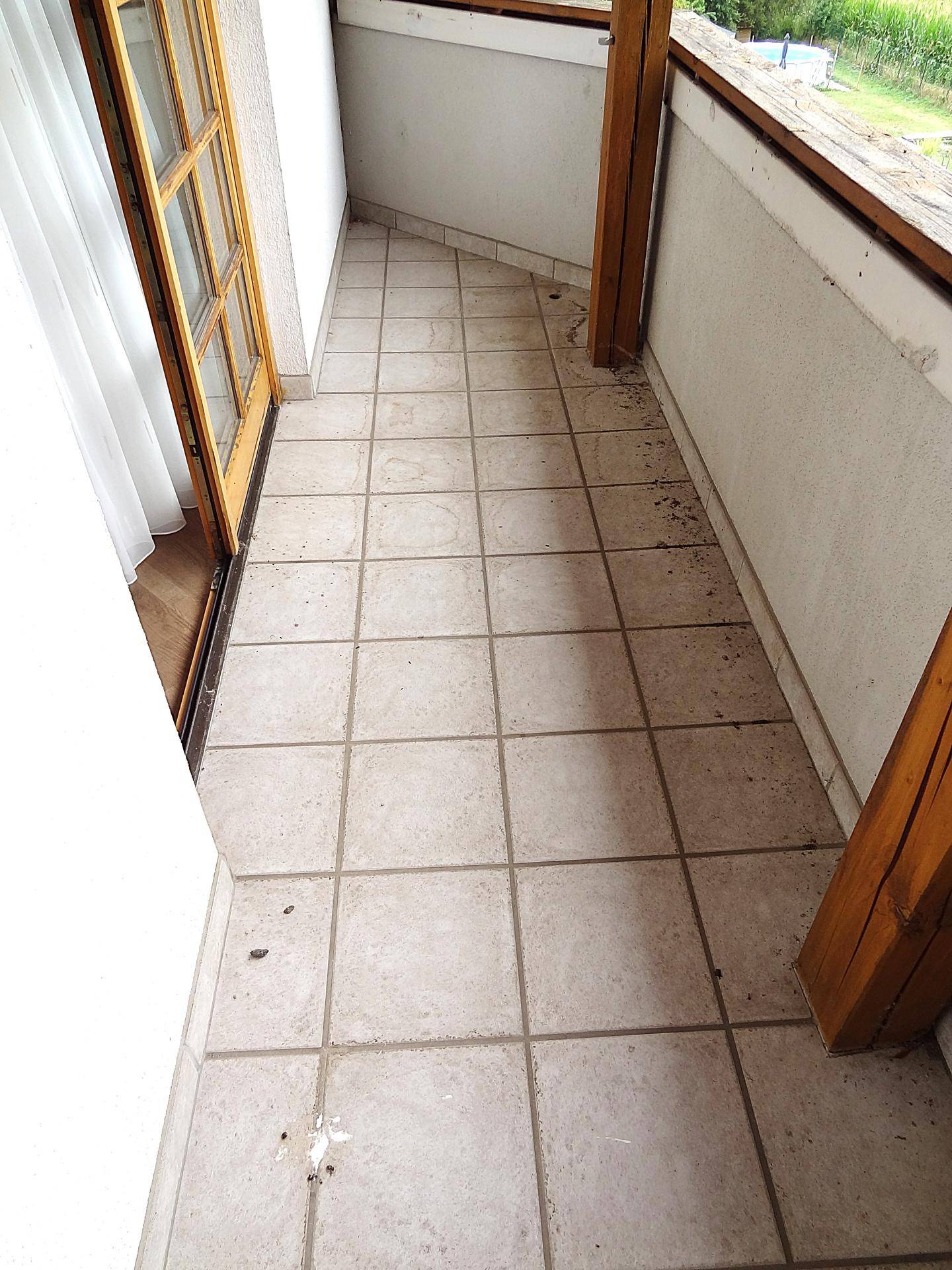 Kleiner Balkon mit Fliesenboden und Holzgeländer, bereit zur Gestaltung.
