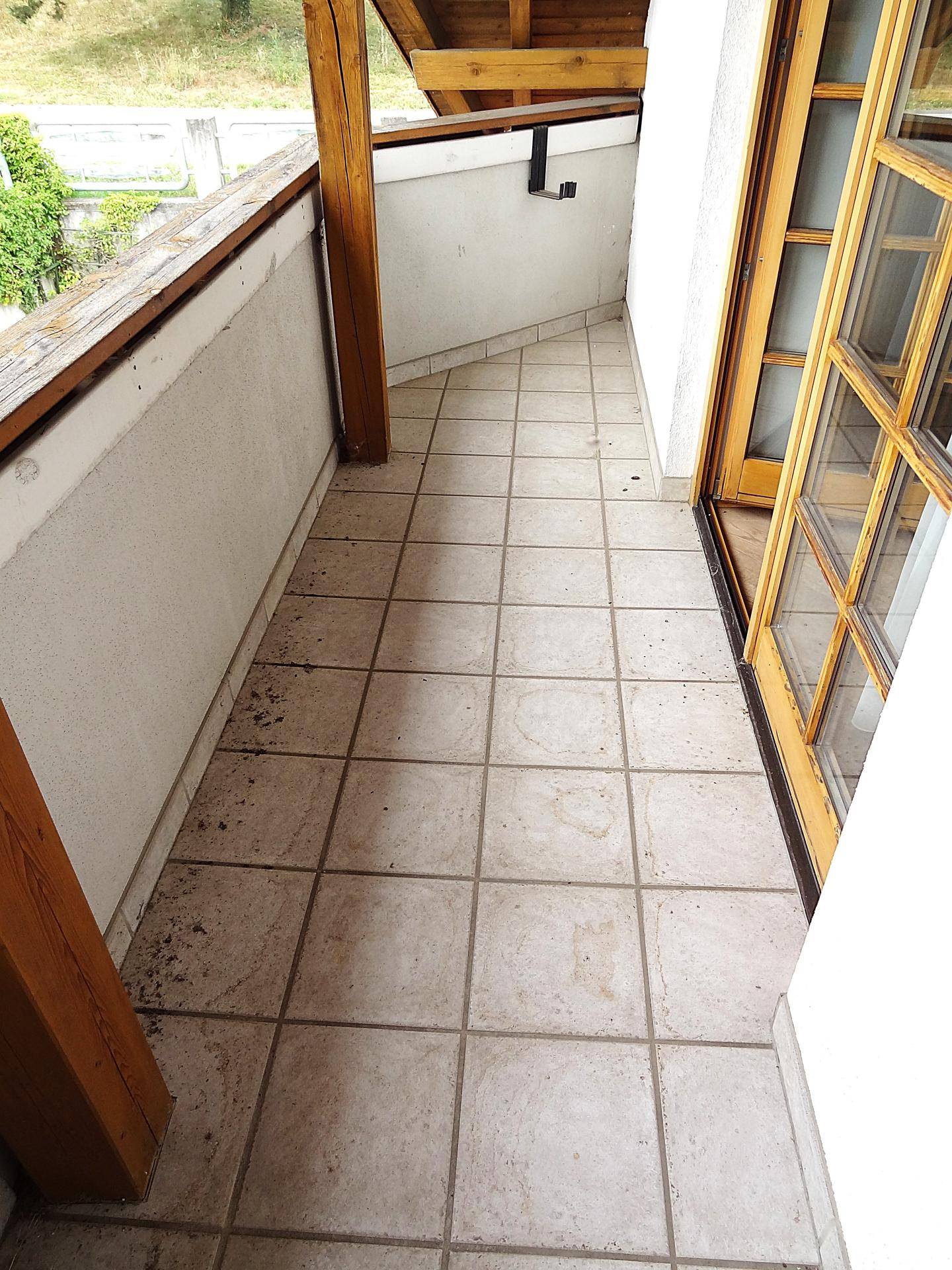 Gefliester Balkon mit Holzgeländer und Blick ins Grüne, ideal für Entspannung.