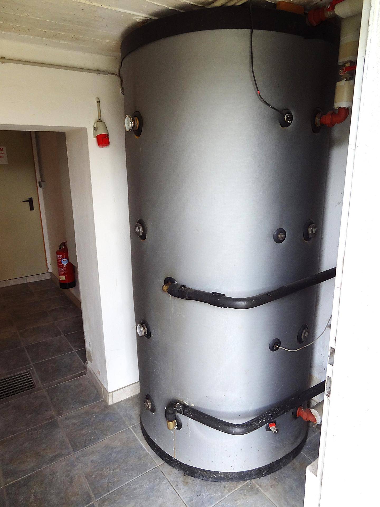 Technikraum im Keller mit großem Warmwasserspeicher und Fliesenboden.