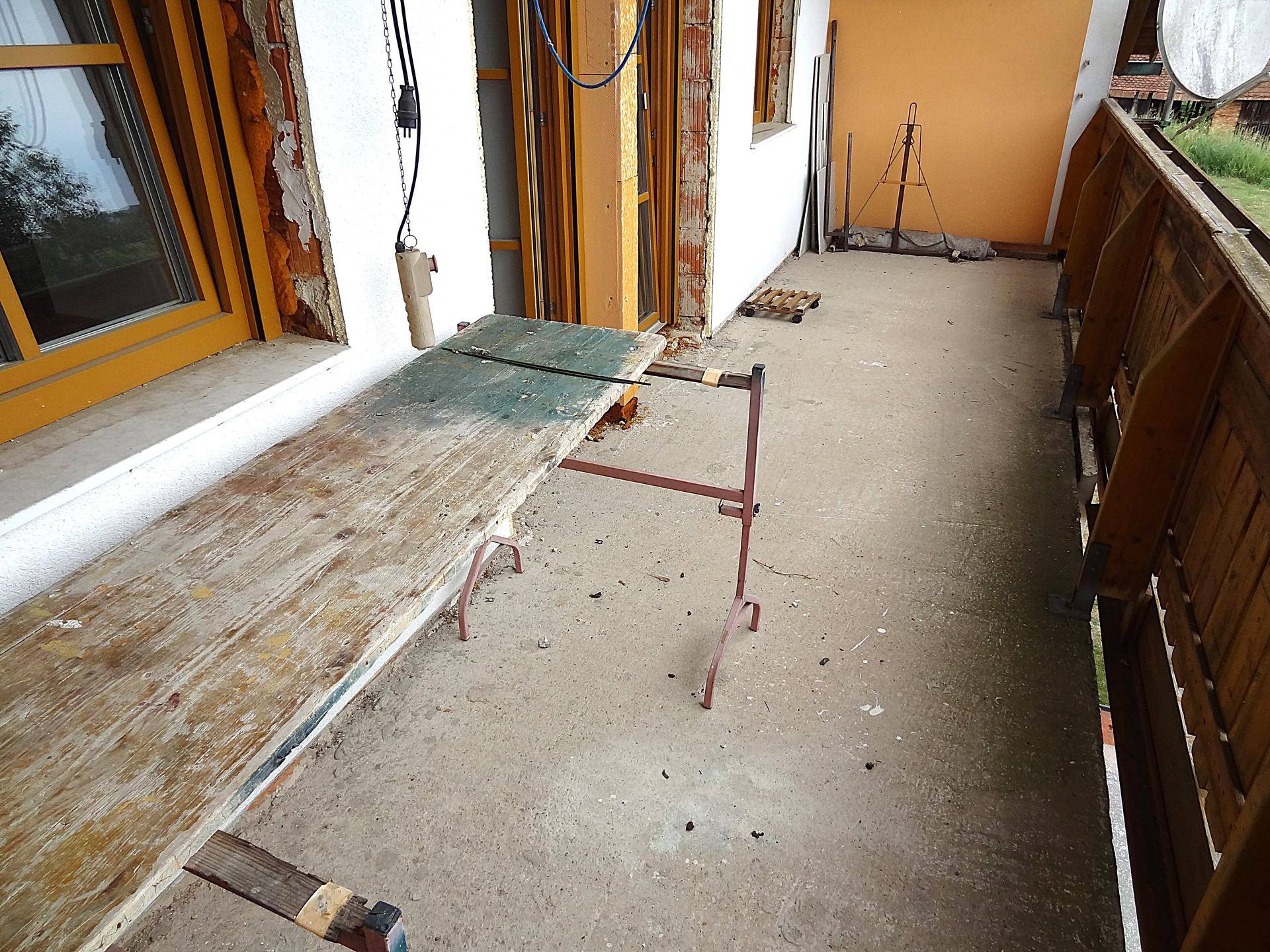 Große Terrasse mit Betonboden und provisorischer Arbeitsfläche, ideal für Renovierungsprojekte.