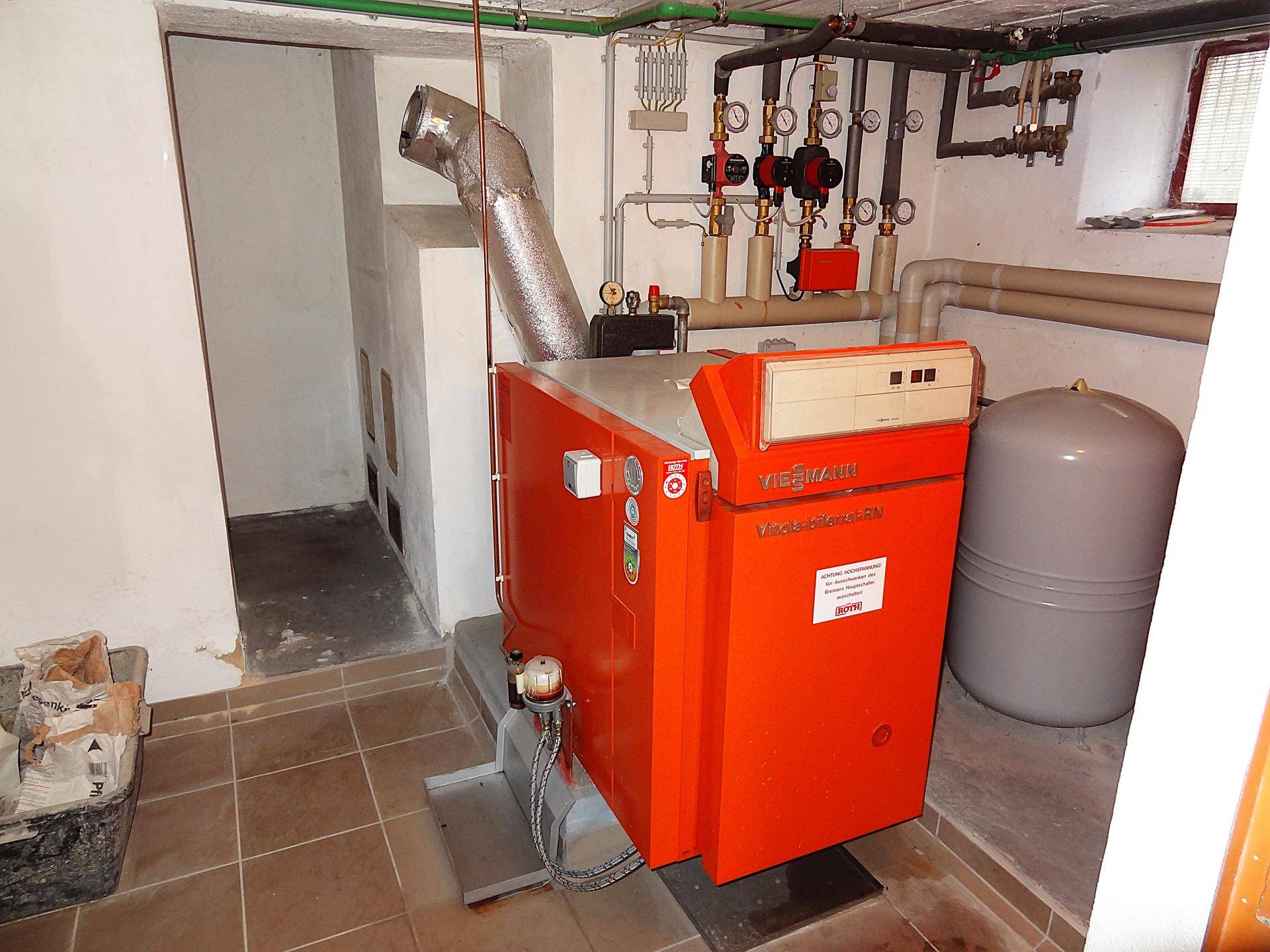 Heizraum mit einem großen orangefarbenen Viessmann-Heizkessel und umfangreicher Verrohrung.