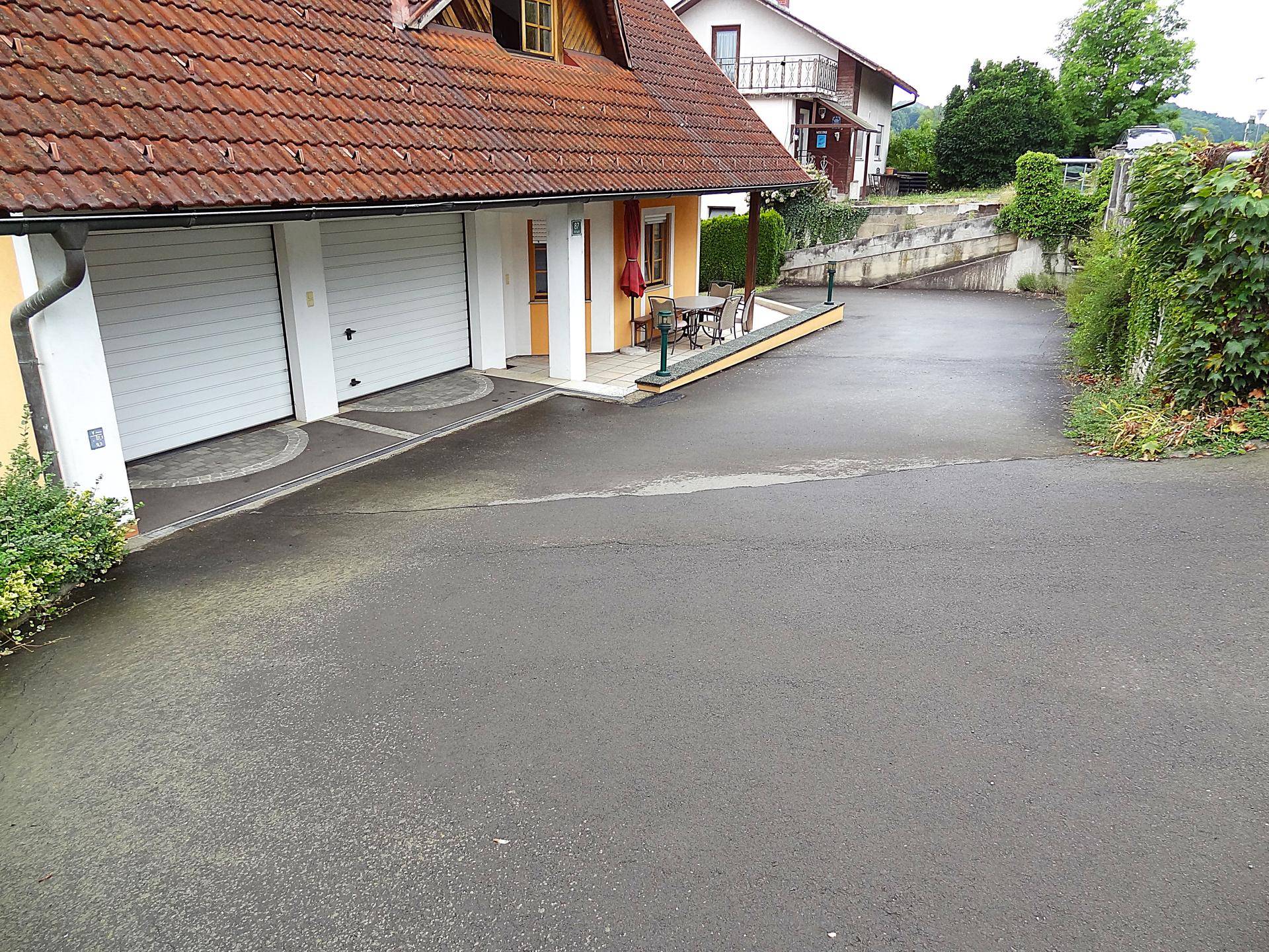 Weitläufige Zufahrt zum Haus mit Doppelgarage und angrenzendem Außenbereich.