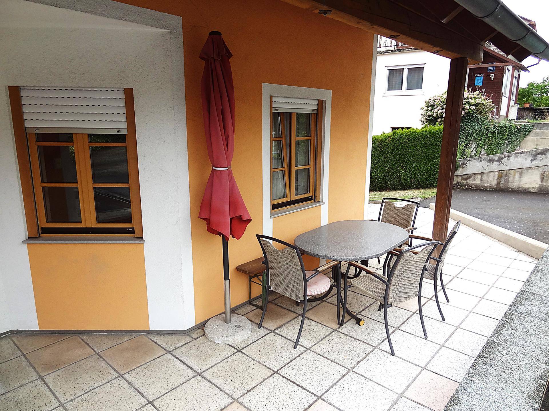 Gemütliche Terrasse mit Tisch und Stühlen, ideal für Mahlzeiten im Freien.