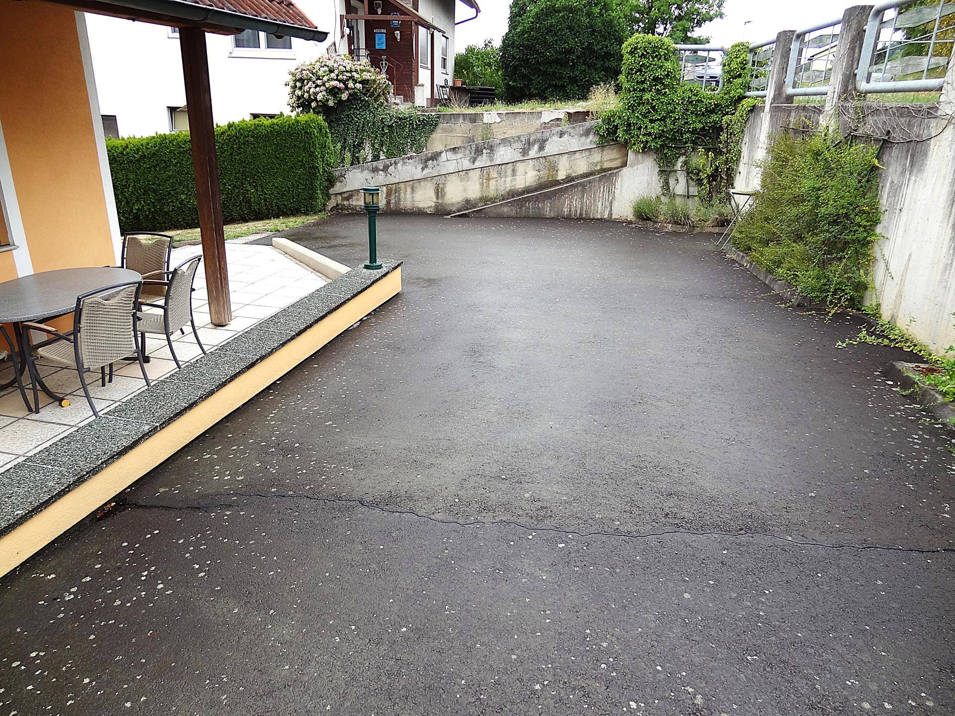 Große asphaltierte Fläche vor dem Haus, nutzbar als Parkplatz oder Zufahrt.