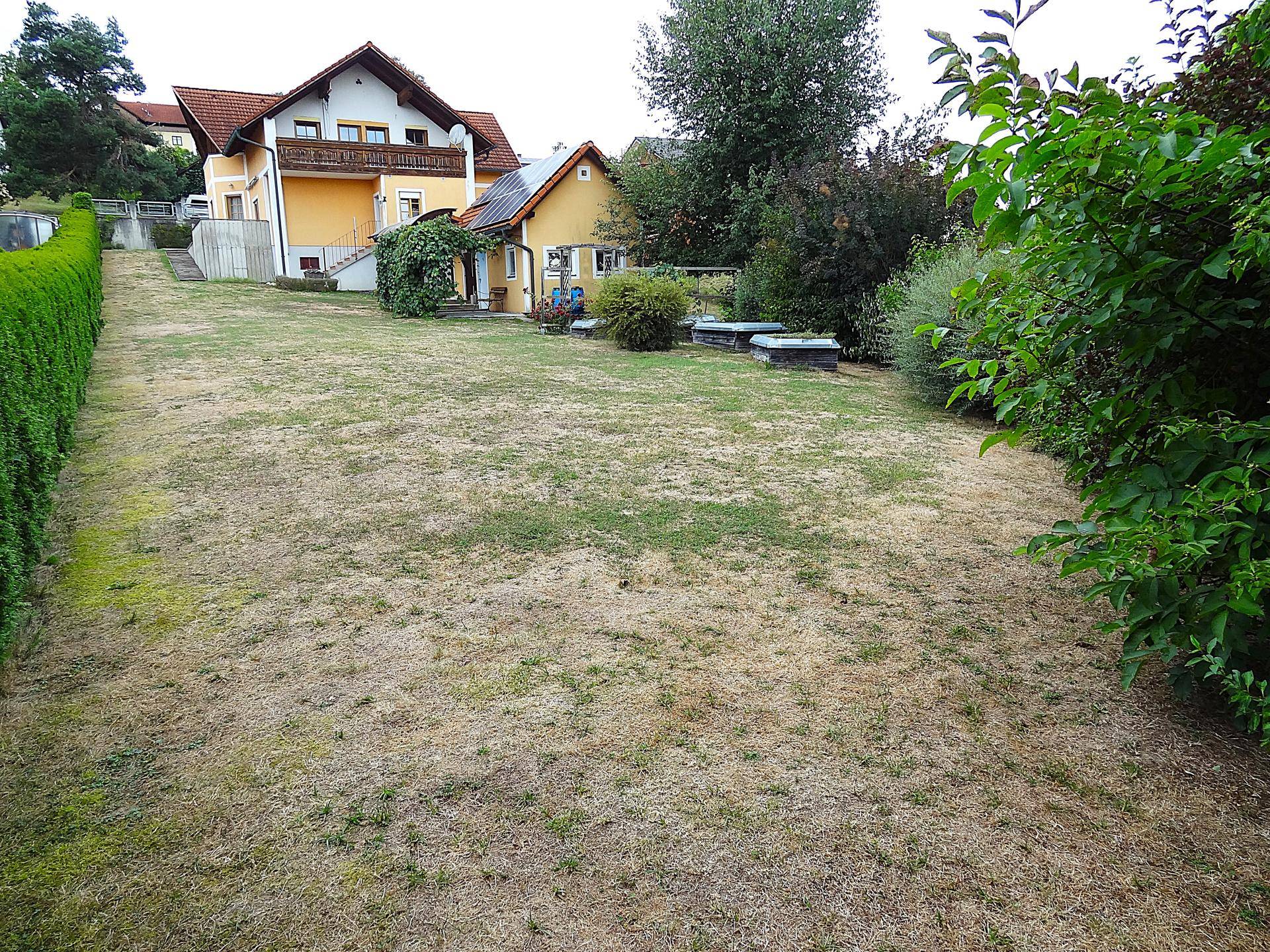 Großer Garten mit Rasenfläche und Blick auf das Hauptgebäude im Hintergrund.