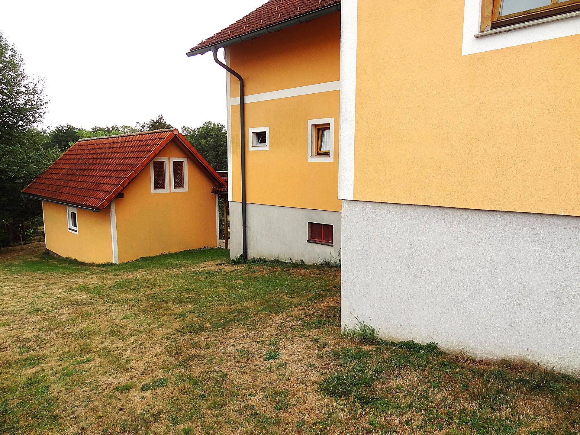 Zwei Gebäude mit gelber Fassade und rotem Ziegeldach, umgeben von Rasen.