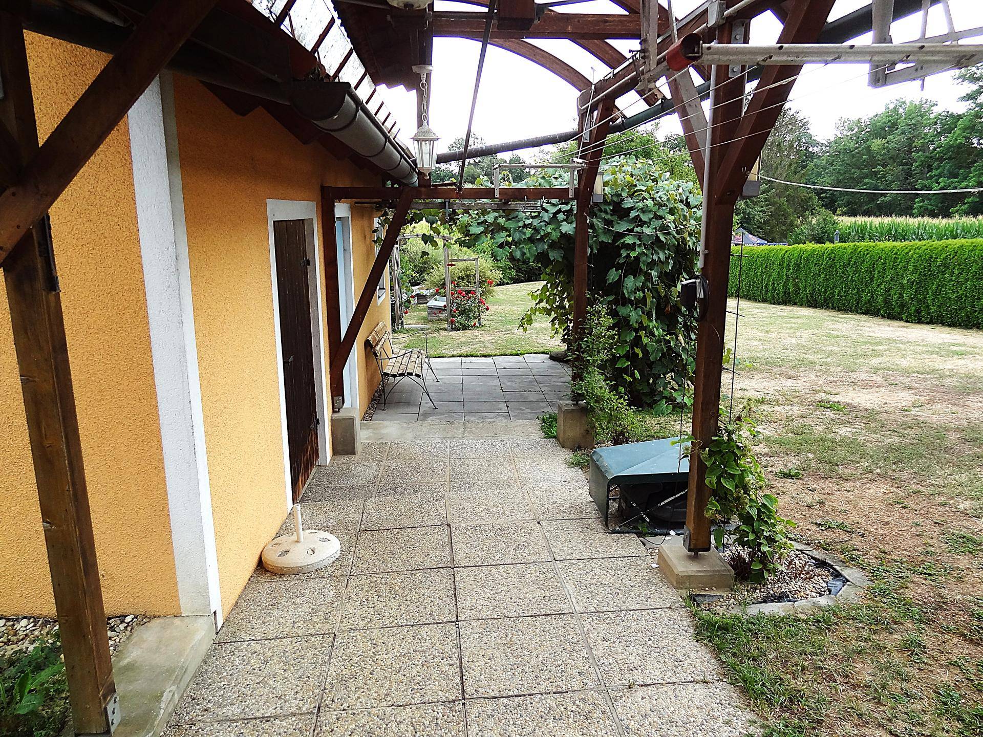 Überdachte Terrasse mit Fliesenboden und direktem Zugang zum Garten.