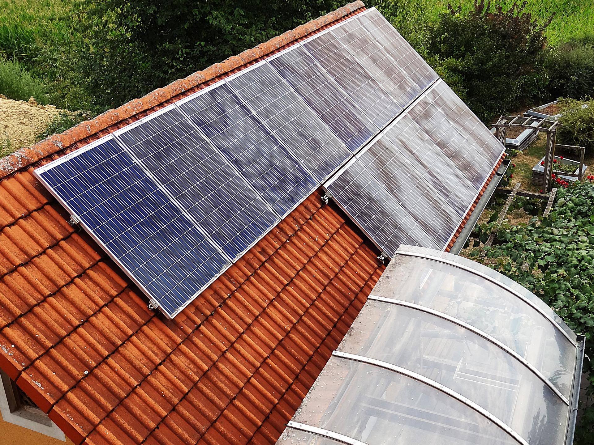 Nahaufnahme von Photovoltaikmodulen auf einem Ziegeldach mit Dachfenster.