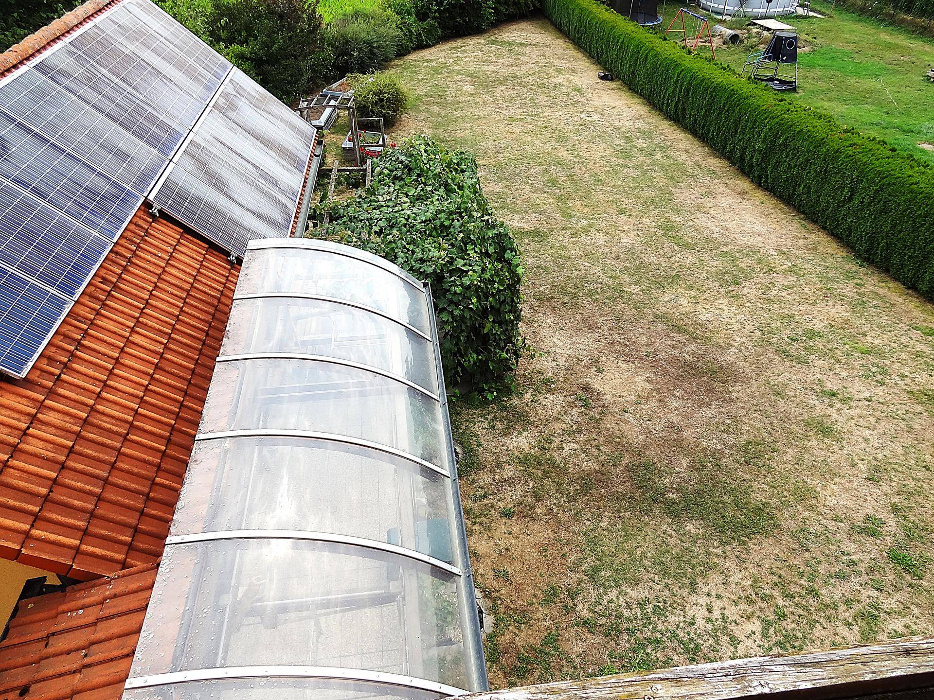 Gartenansicht von oben mit Photovoltaikanlage auf dem Dach und überdachtem Bereich.