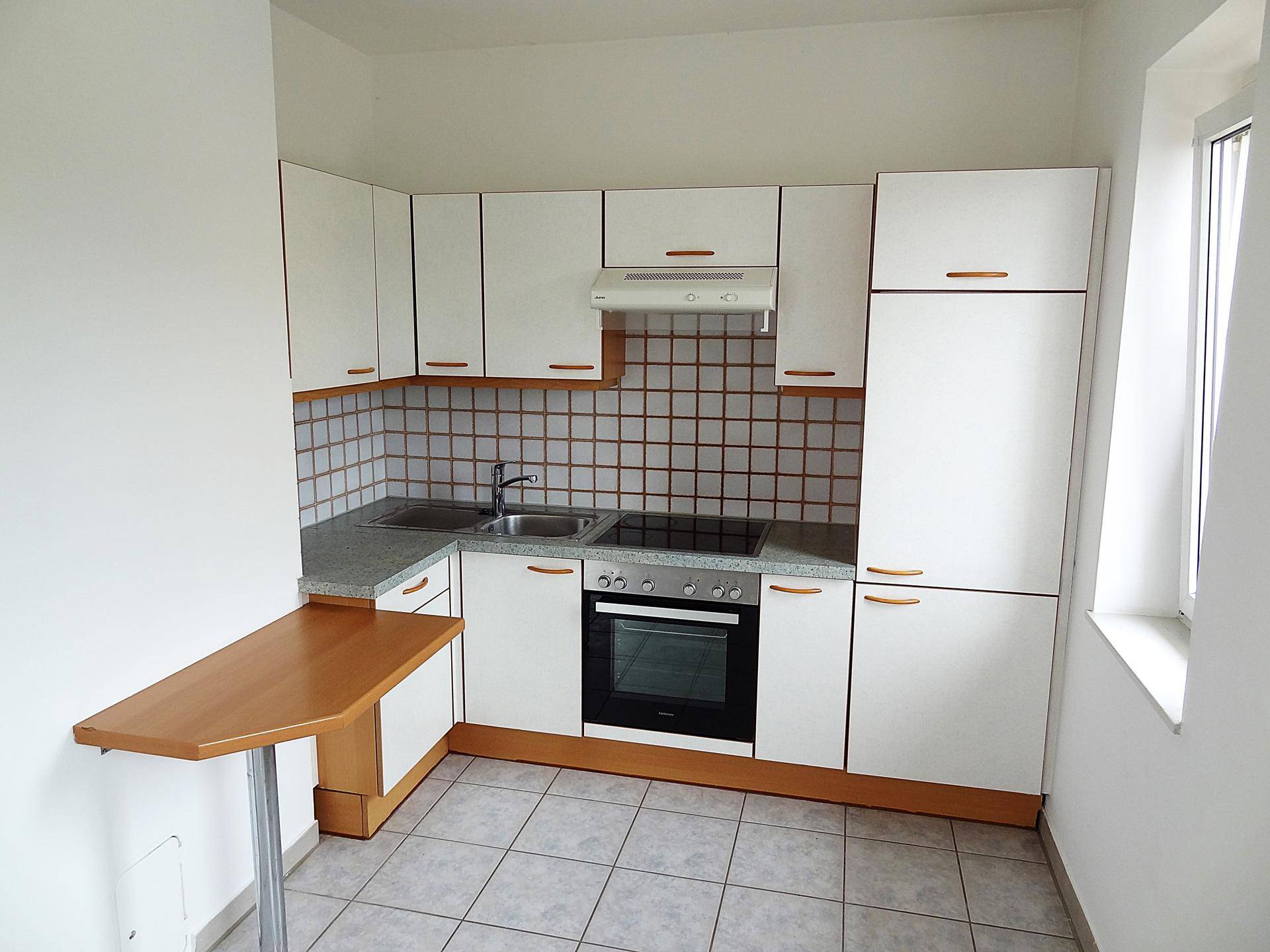 Kleine Einbauküche mit weißen Schränken, Fliesenrückwand und integrierten Geräten.