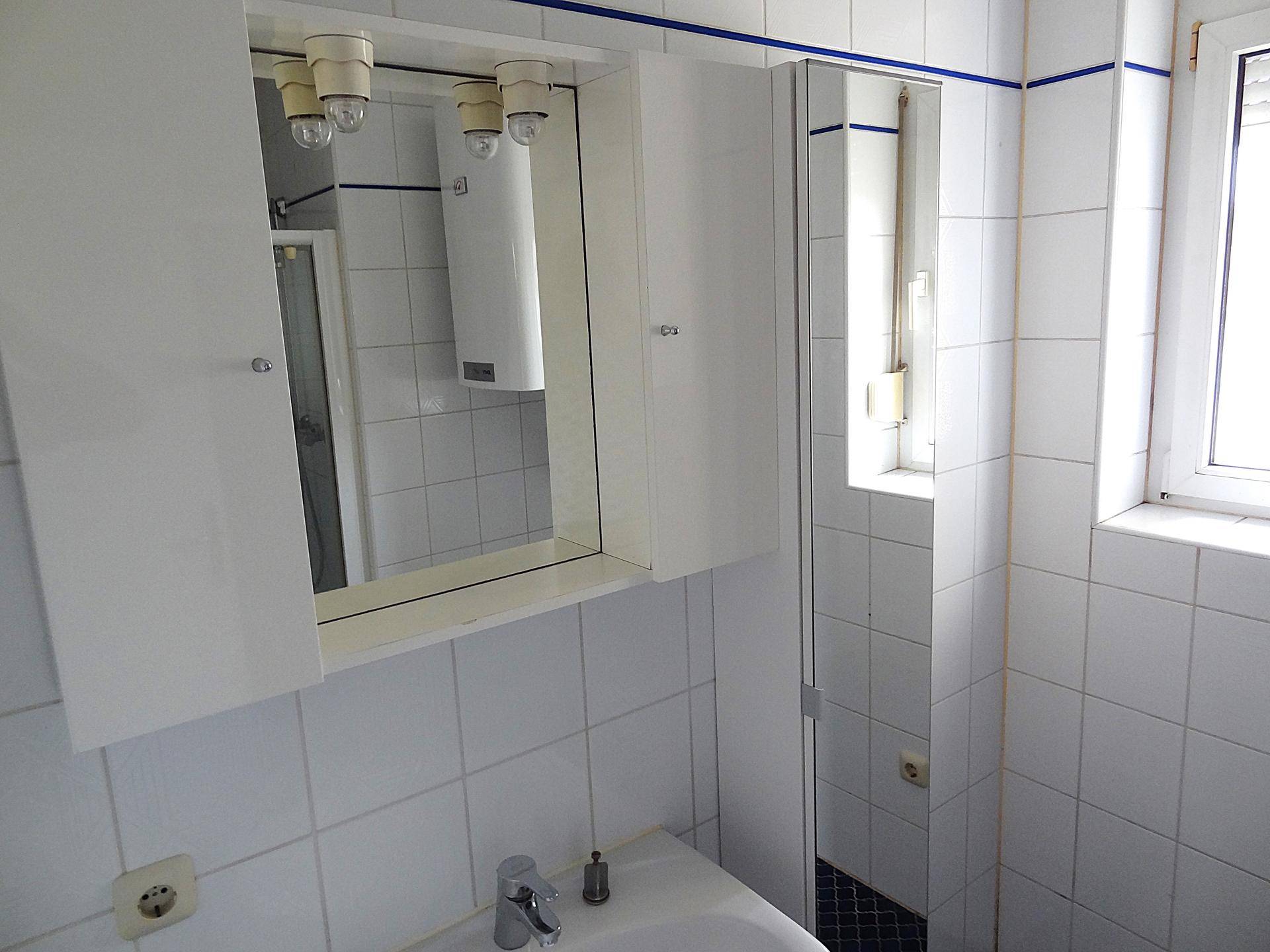 Badezimmer mit Waschbecken, Spiegelschrank und weißen Fliesen, funktional und hell.