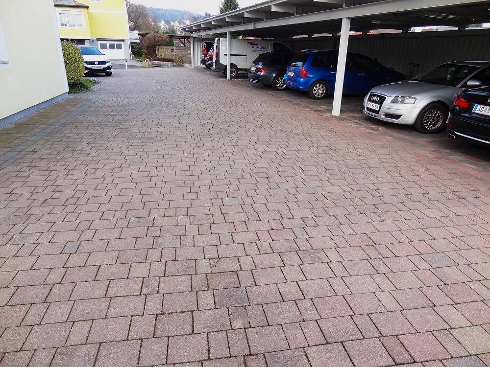 Große gepflasterte Fläche, die zum Carport führt und ausreichend Parkmöglichkeiten bietet.