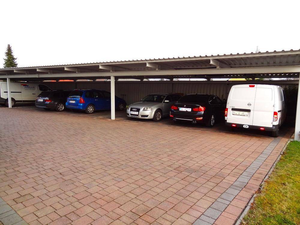 Carport mit mehreren Fahrzeugen, die sicher und geschützt unter dem Dach abgestellt sind.