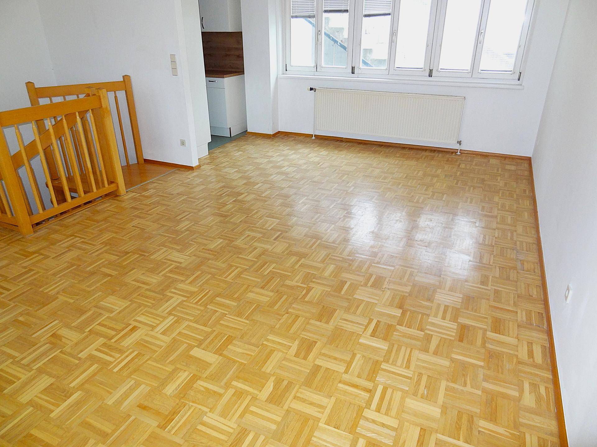 Heller Wohnbereich mit gepflegtem Parkettboden und viel Tageslicht durch große Fenster.