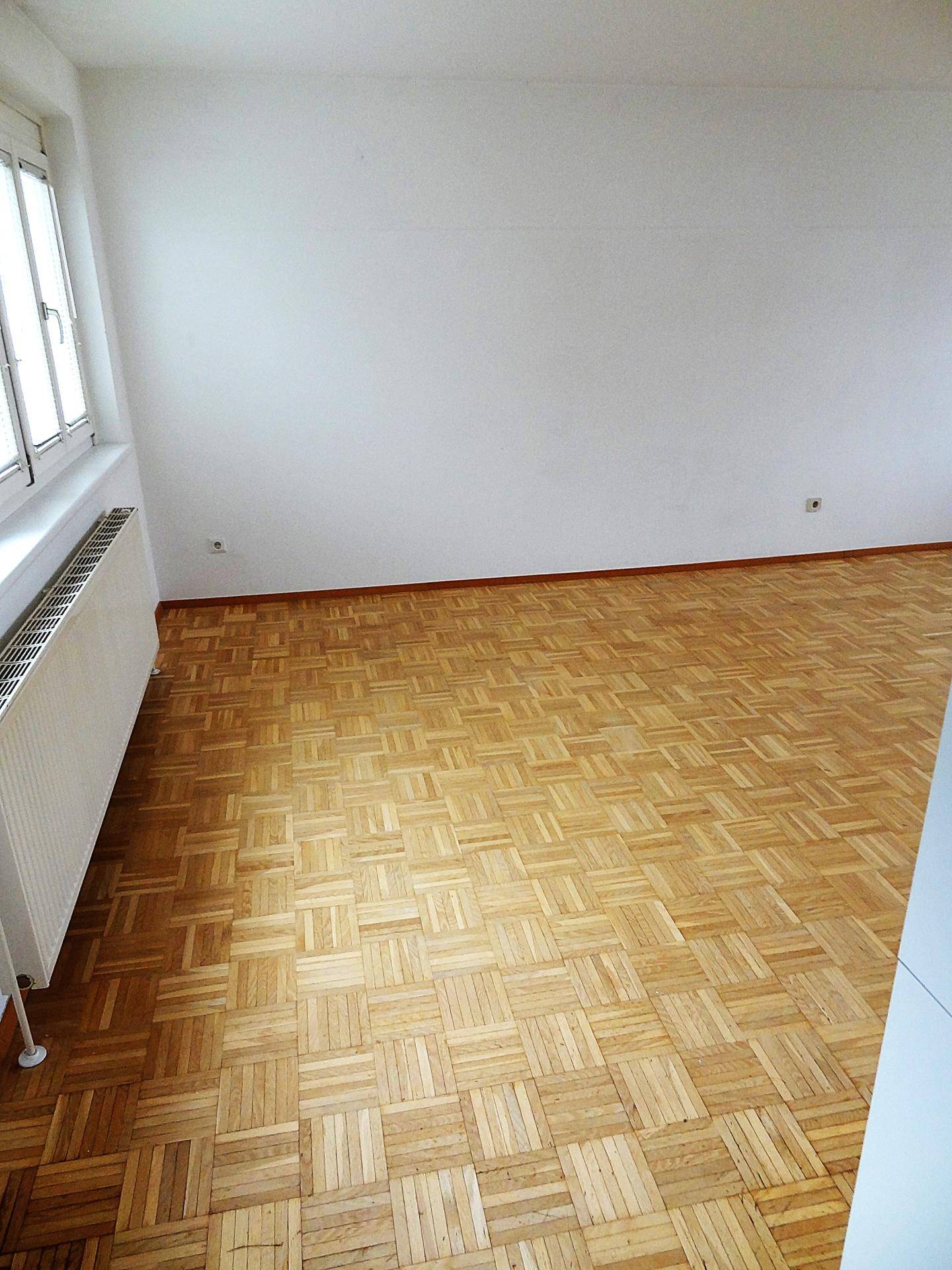 Nahaufnahme des hellen Parkettbodens und der weißen Wände im Wohnbereich.