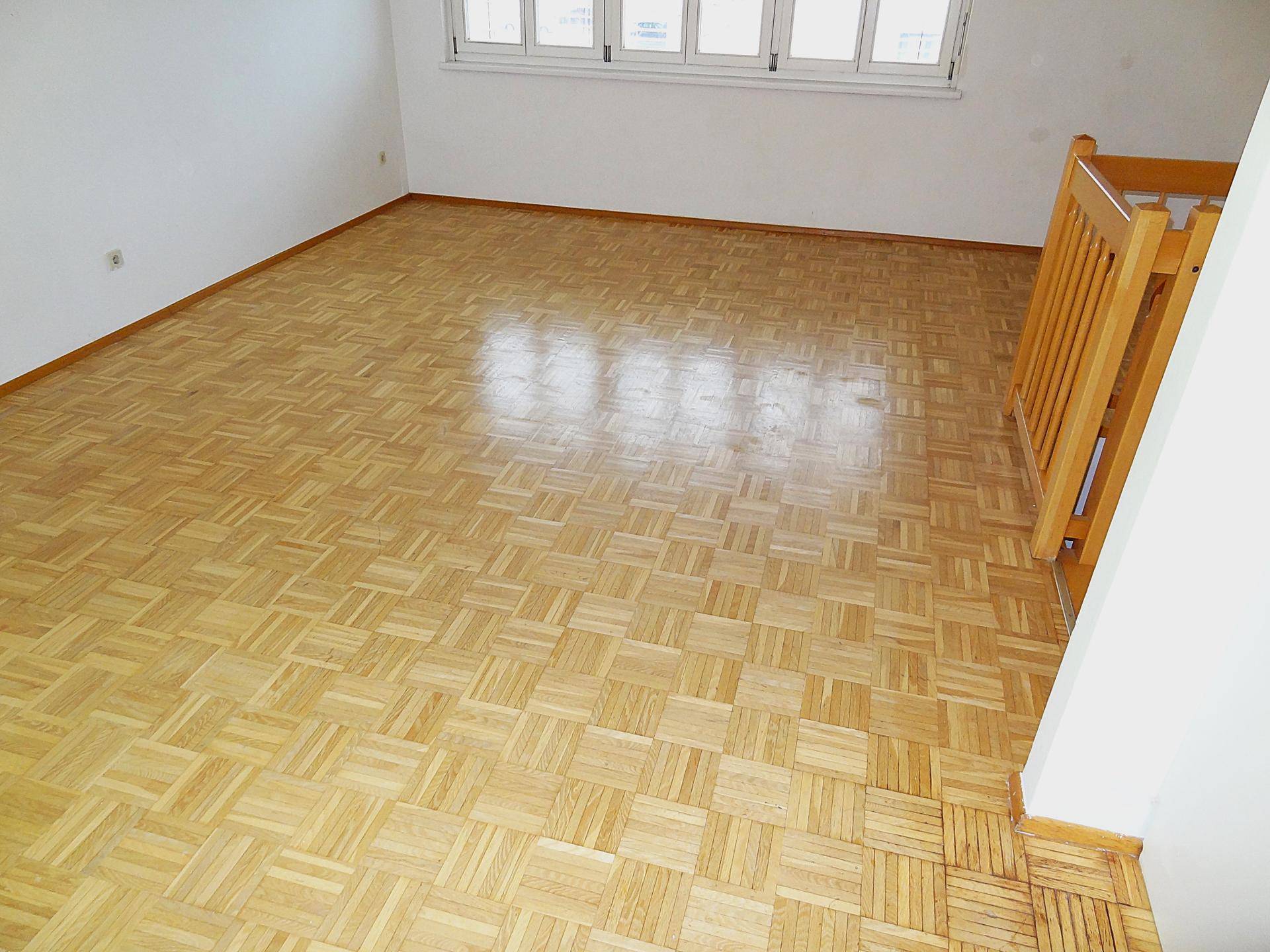 Heller Wohnbereich mit Parkettboden und Holztreppe, die in eine andere Etage führt.