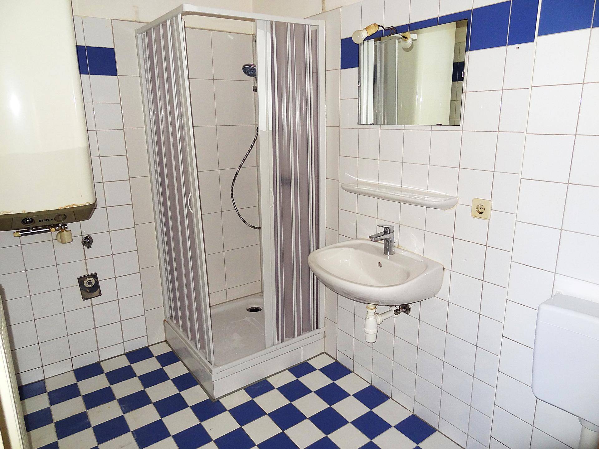 Funktionales Badezimmer mit Duschkabine, Waschbecken und WC, akzentuiert durch blaue Fliesen.