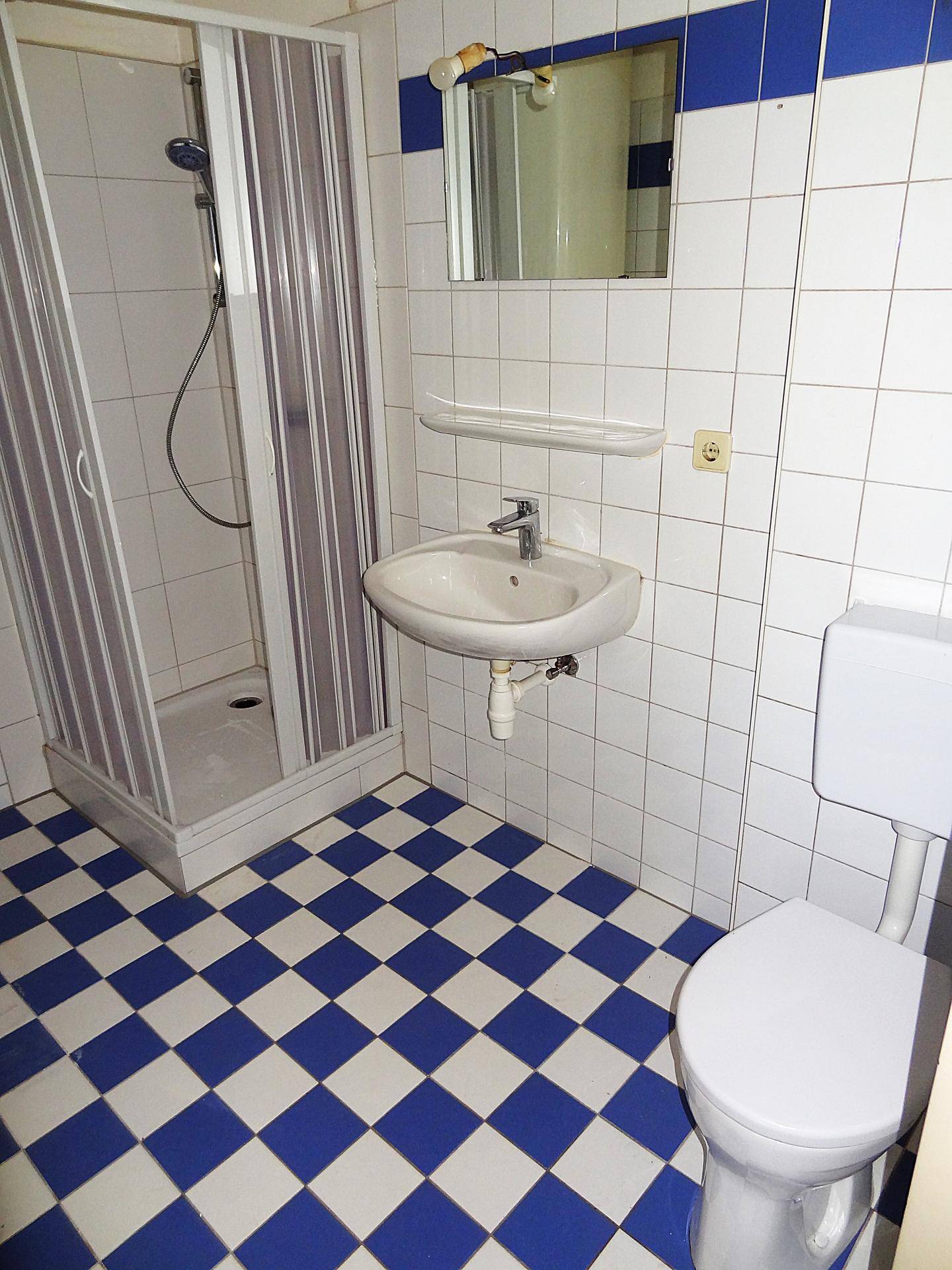 Praktisches Badezimmer mit Duschkabine, Waschbecken und WC, betont durch blaue Akzentfliesen.