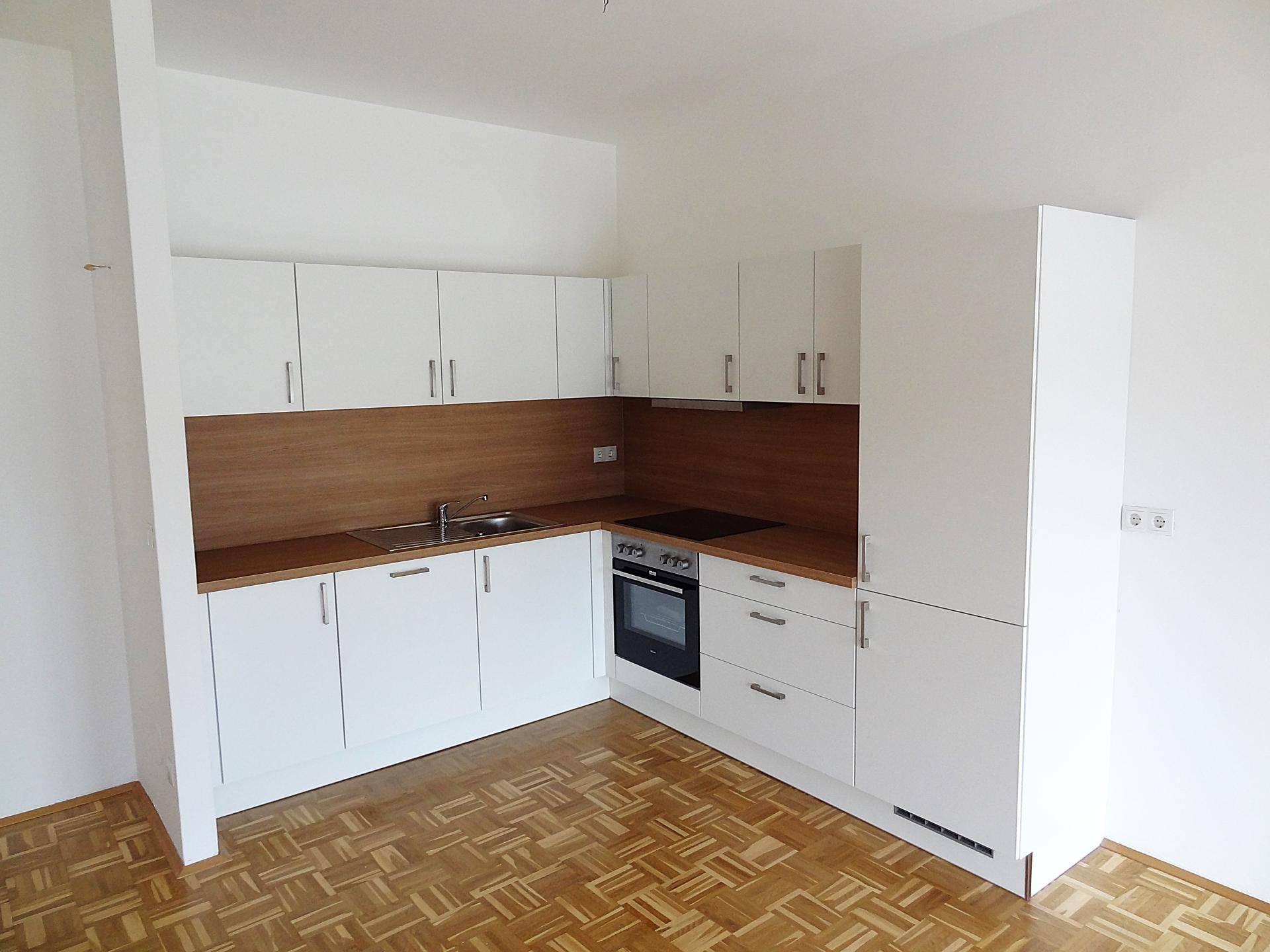 Helle Küche mit weißen Fronten, Holzdetails und funktionaler Ausstattung in einem offenen Raum.