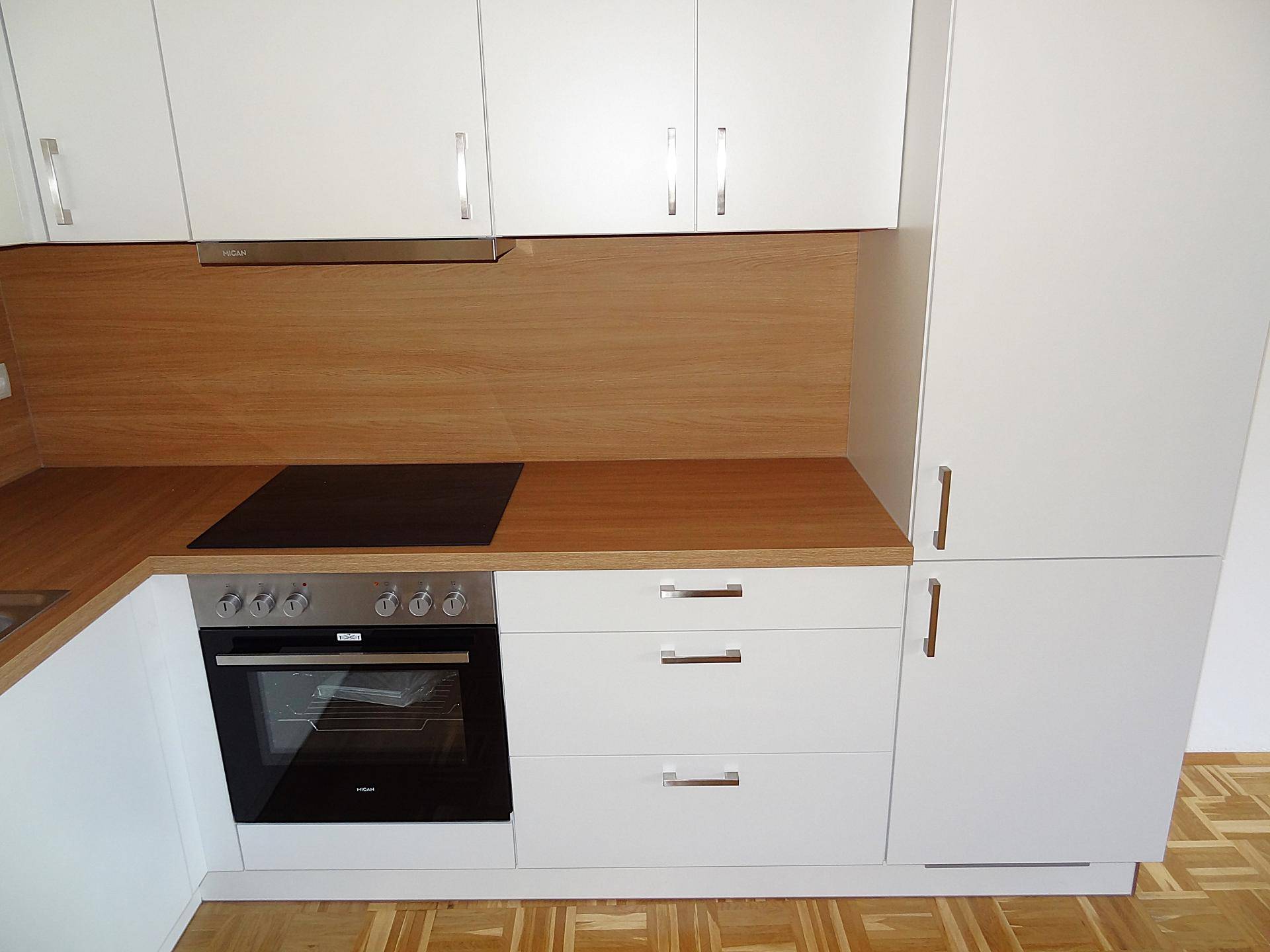 Nahaufnahme des Backofens und Induktionskochfelds in der weißen Einbauküche mit hohem Schrank.