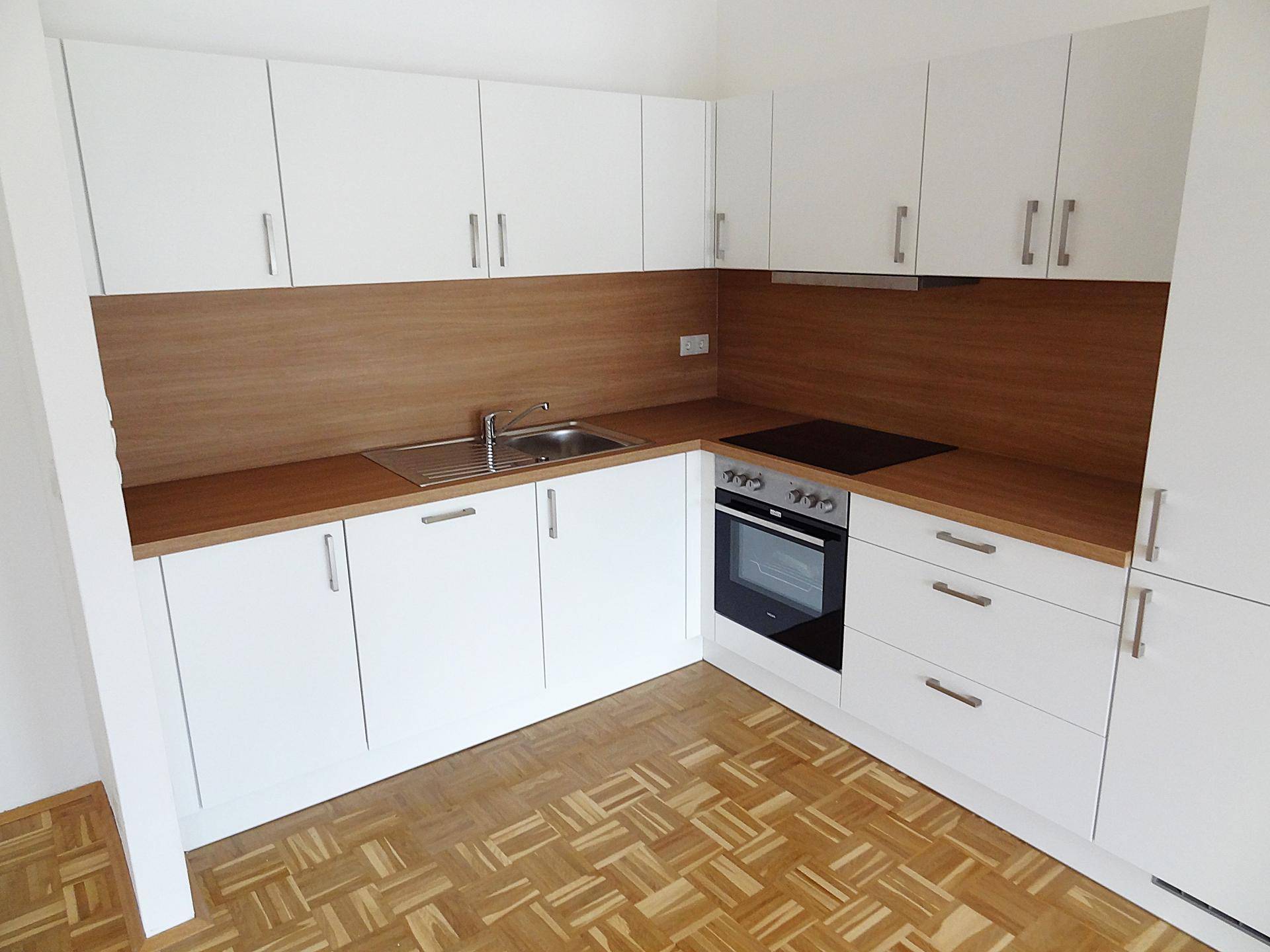 Vollständige Ansicht der neuen Einbauküche mit weißen Fronten, Holzdetails und Parkettboden.
