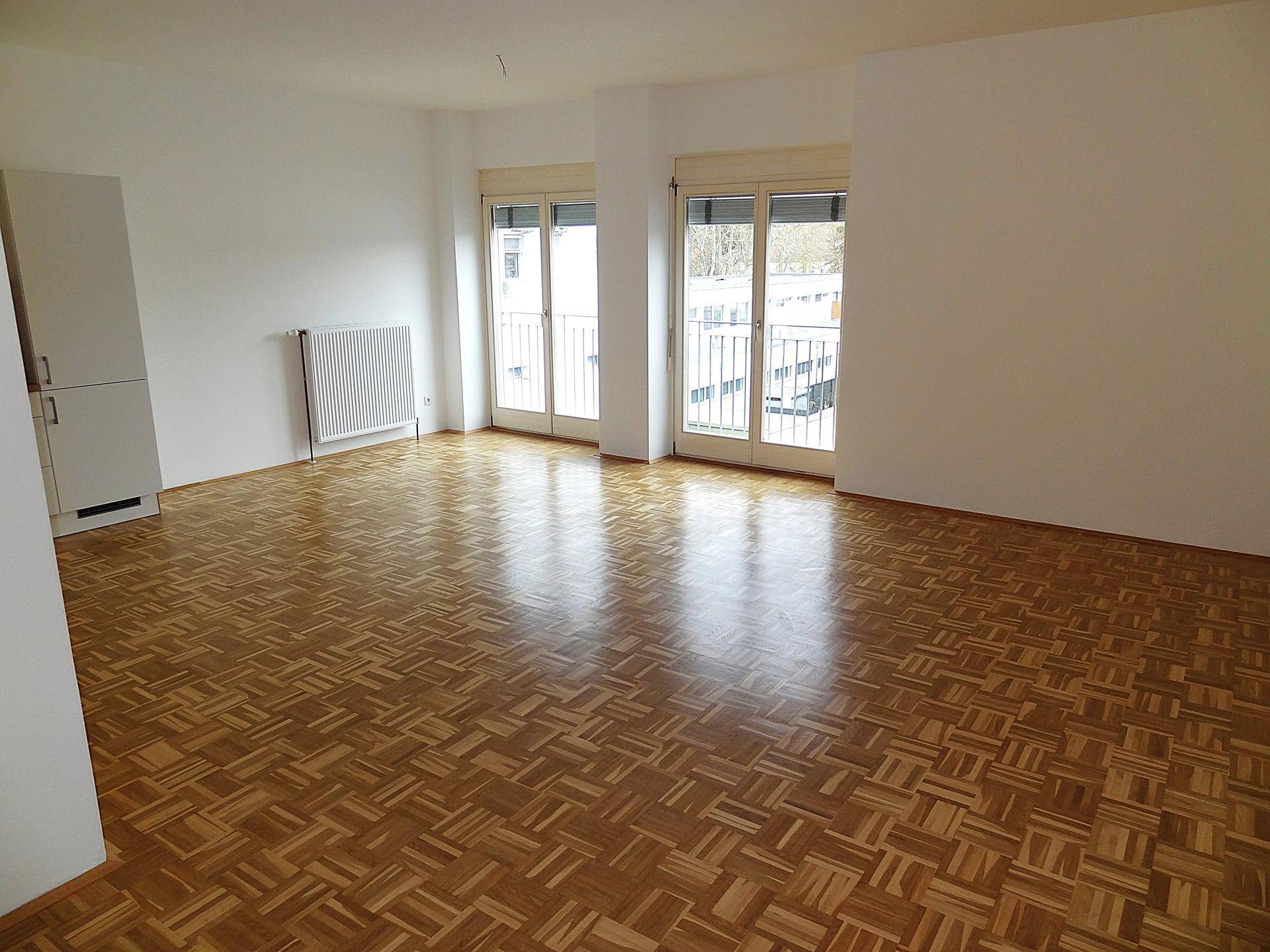 Lichtdurchfluteter Wohnbereich mit Parkettboden und zwei großen Fenstertüren.