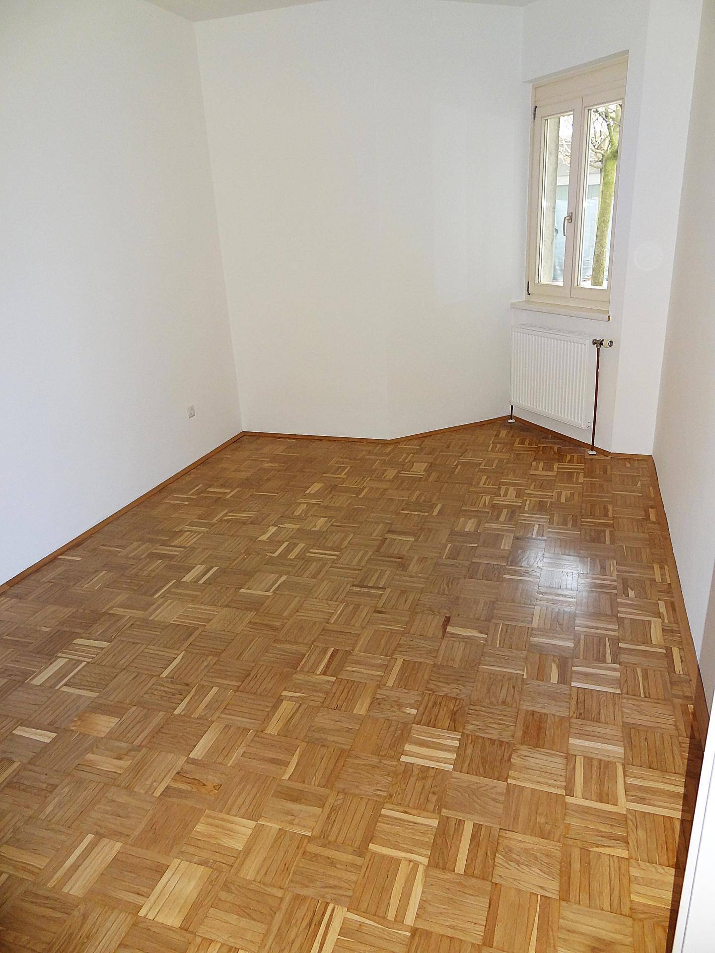 Freundliches Zimmer mit Parkettboden und weißen Wänden, ideal als Kinder- oder Gästezimmer.