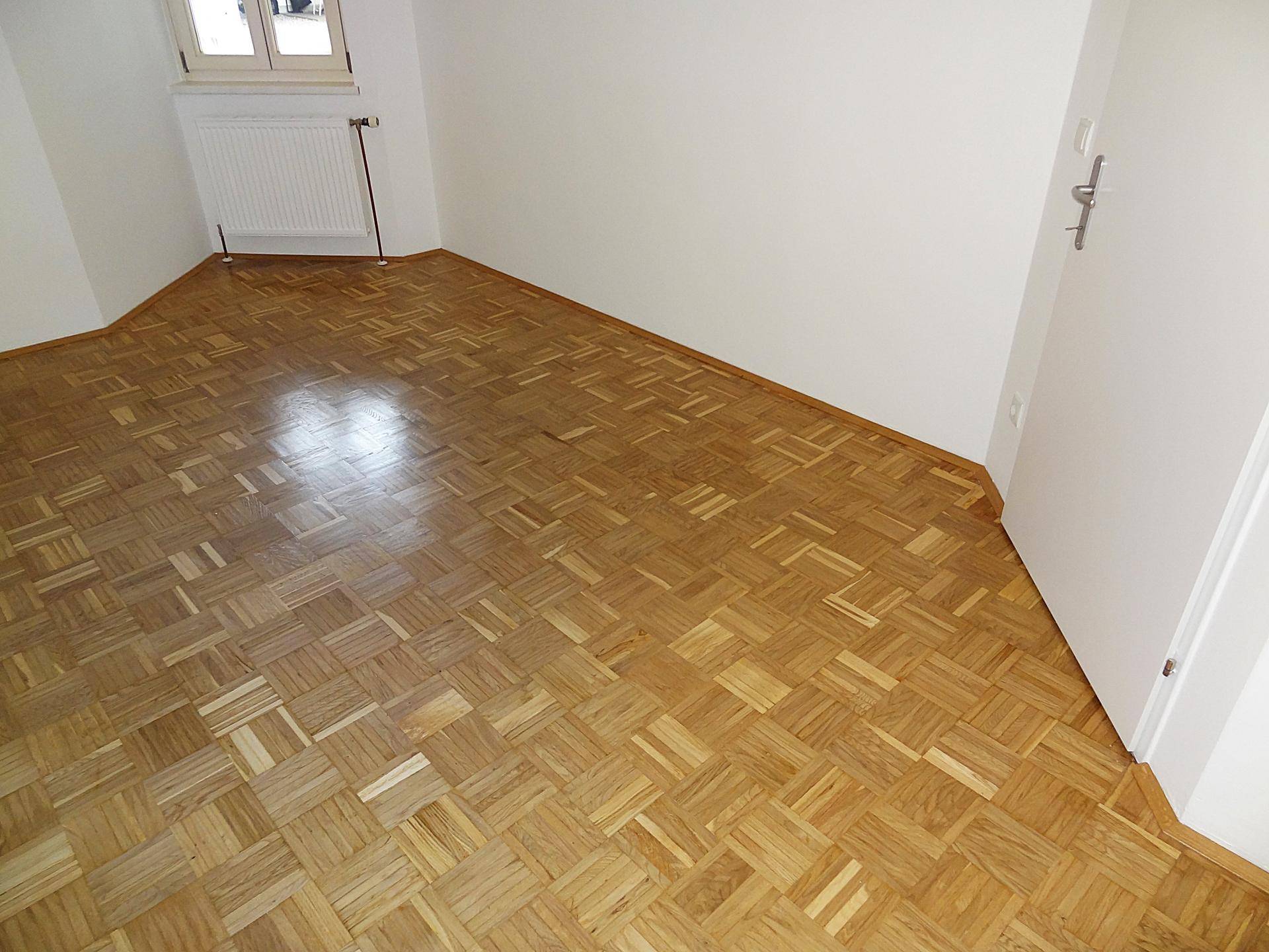 Leeres Zimmer mit Parkettboden und weißen Wänden, bereit zur individuellen Gestaltung.