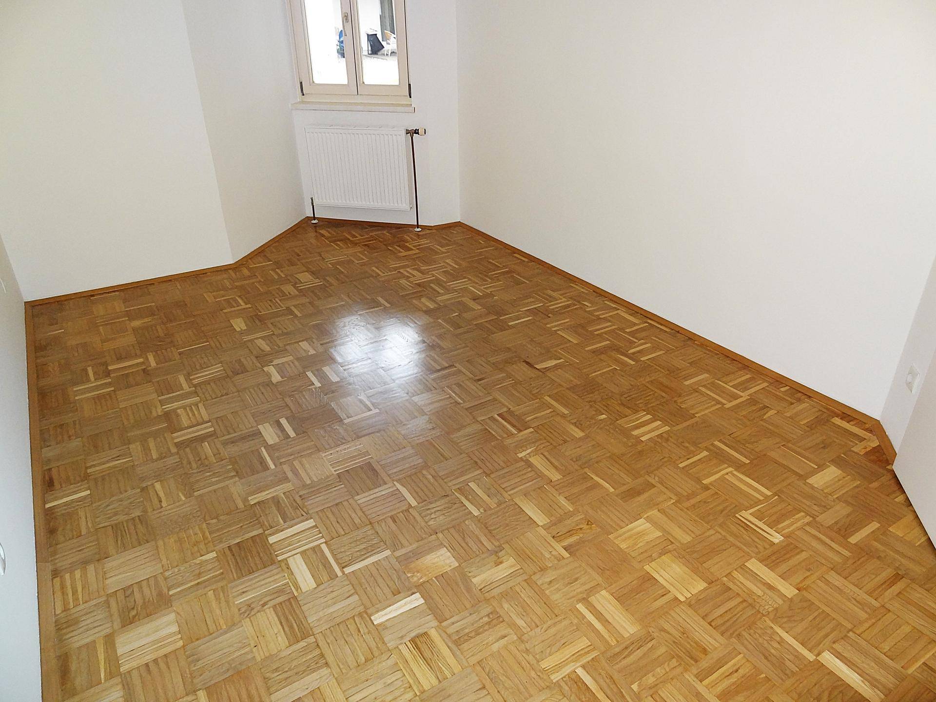 Geräumiges Zimmer mit Parkettboden und weißen Wänden, bietet viel Platz für individuelle Einrichtung.