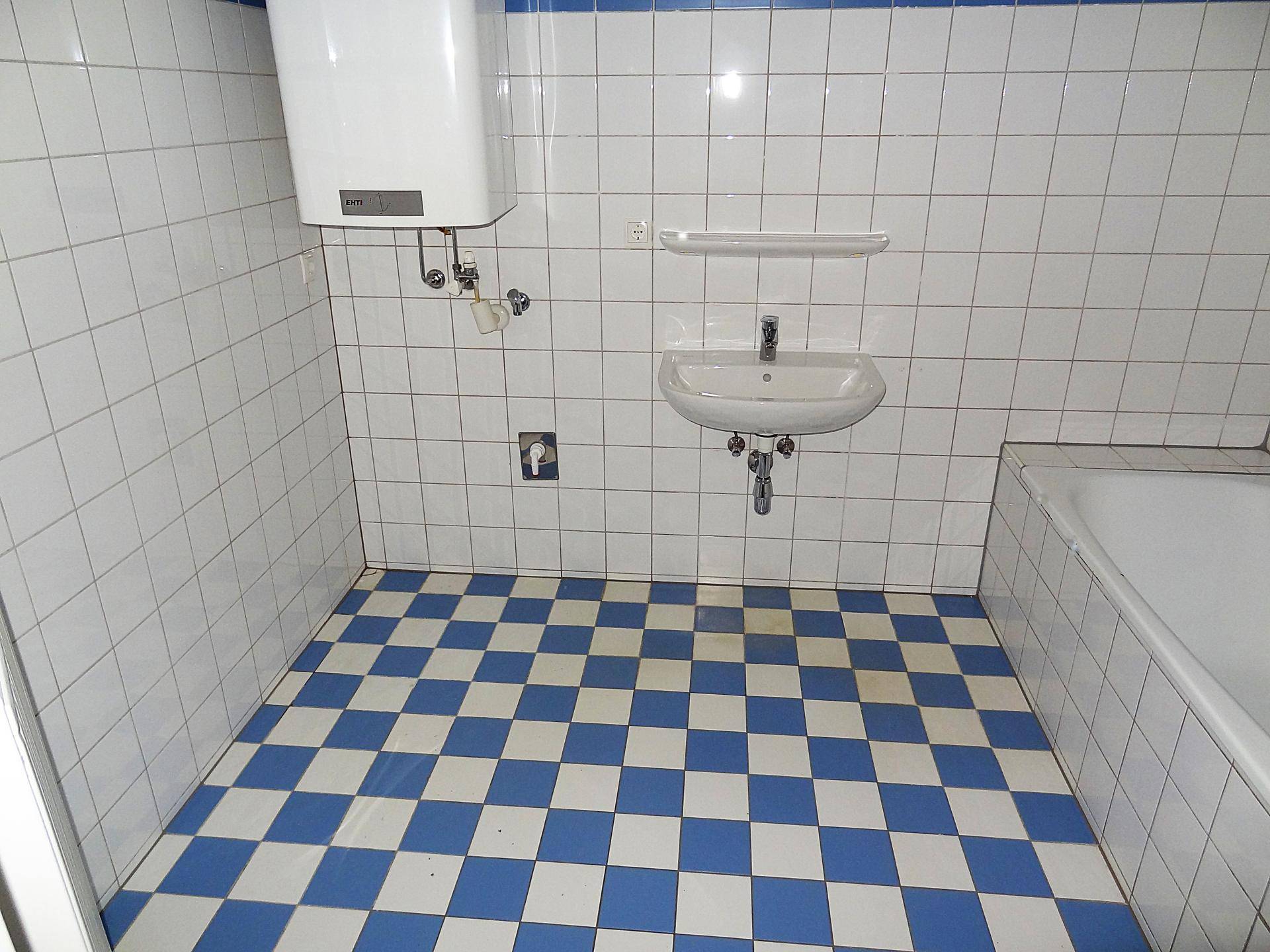 Funktionales Badezimmer mit Badewanne, Waschbecken und charakteristischen blau-weißen Fliesen.