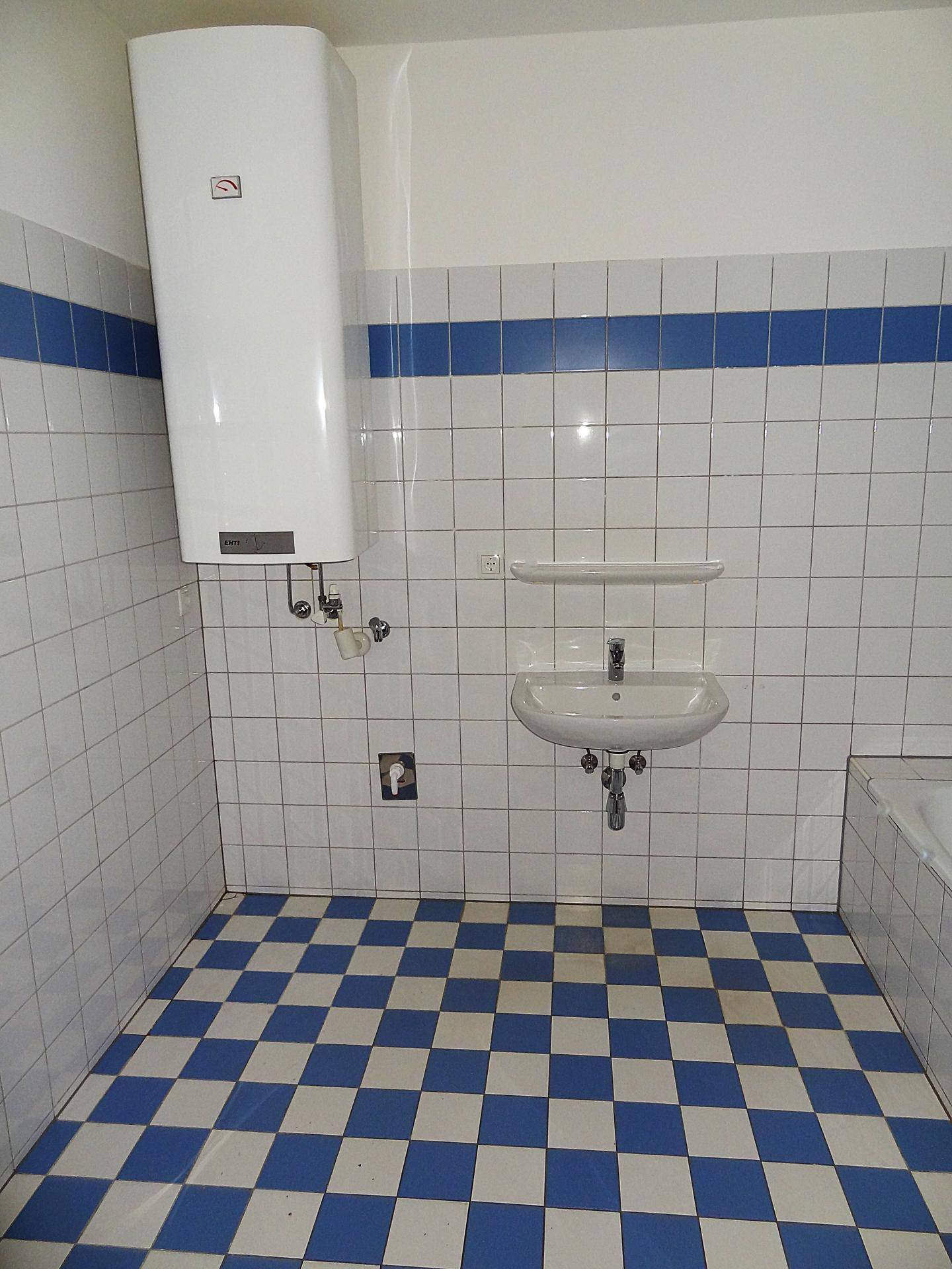 Helles Badezimmer mit Badewanne, Waschbecken und Warmwasserboiler, ausgestattet mit Fliesen.