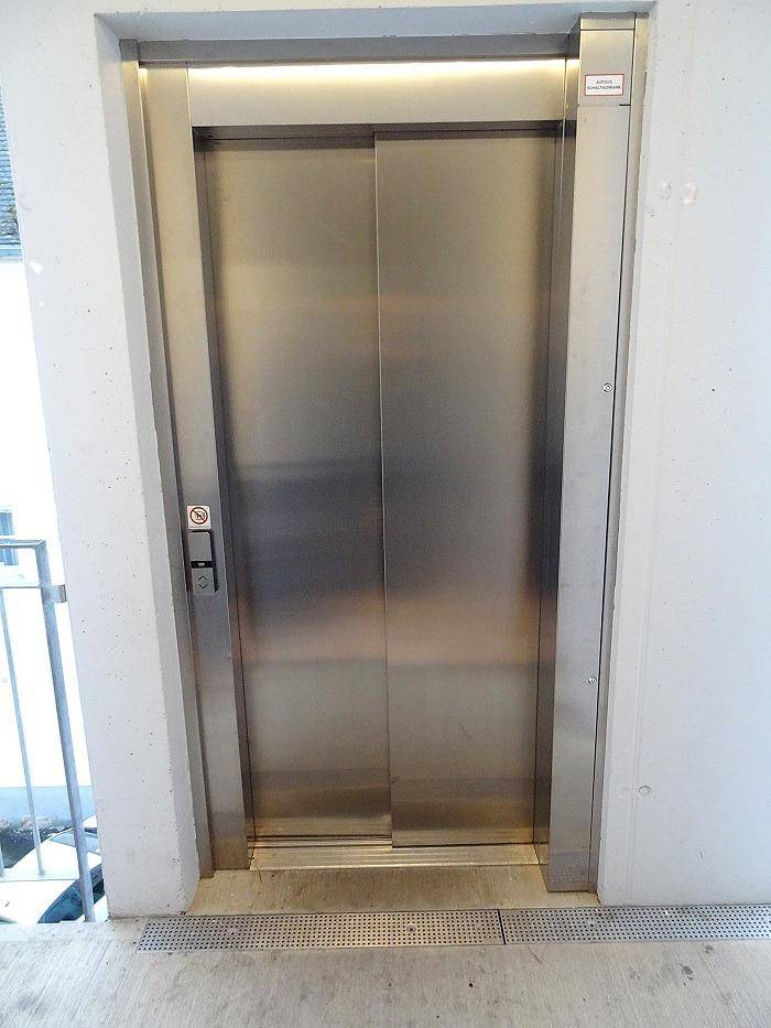 Moderner Aufzug mit Edelstahltüren in einem hellen Gebäude, bereit zur Nutzung.