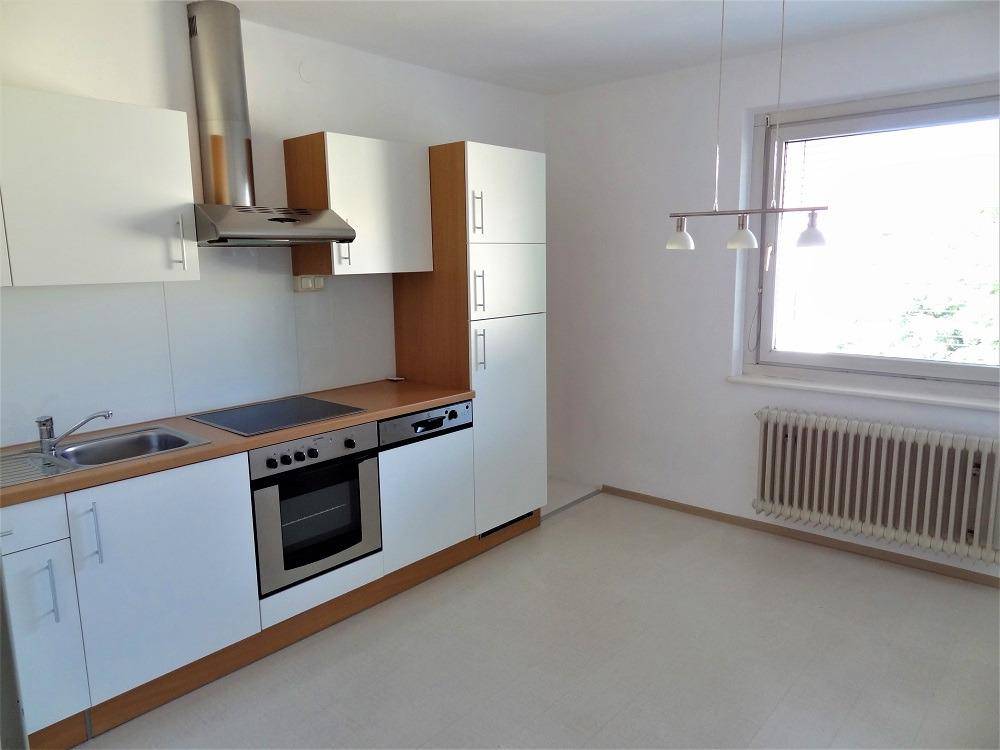 Helle Küche mit Einbaugeräten, Fenster und Heizkörper, bietet Platz für einen Essbereich.