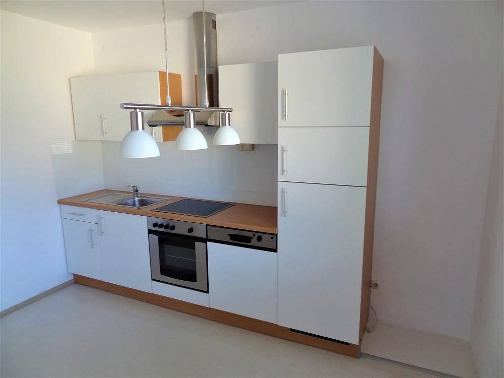 Kompakte Einbauküche mit weißen Fronten, Holzdetails und praktischer Beleuchtung.