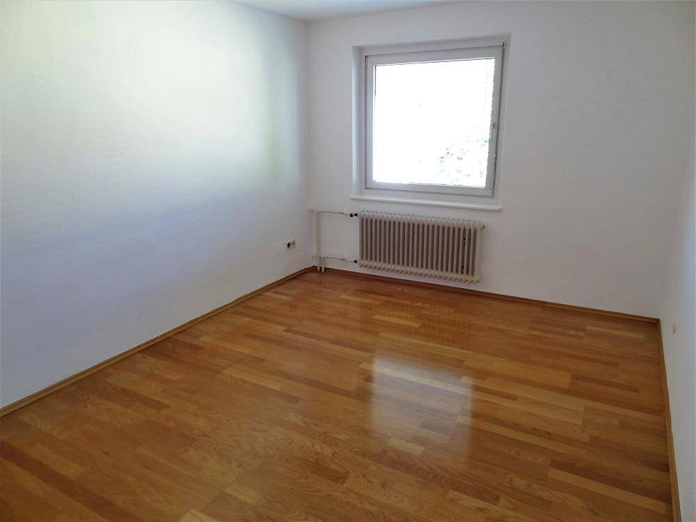 Geräumiger, heller Raum mit schönem Parkettboden und großem Fenster.