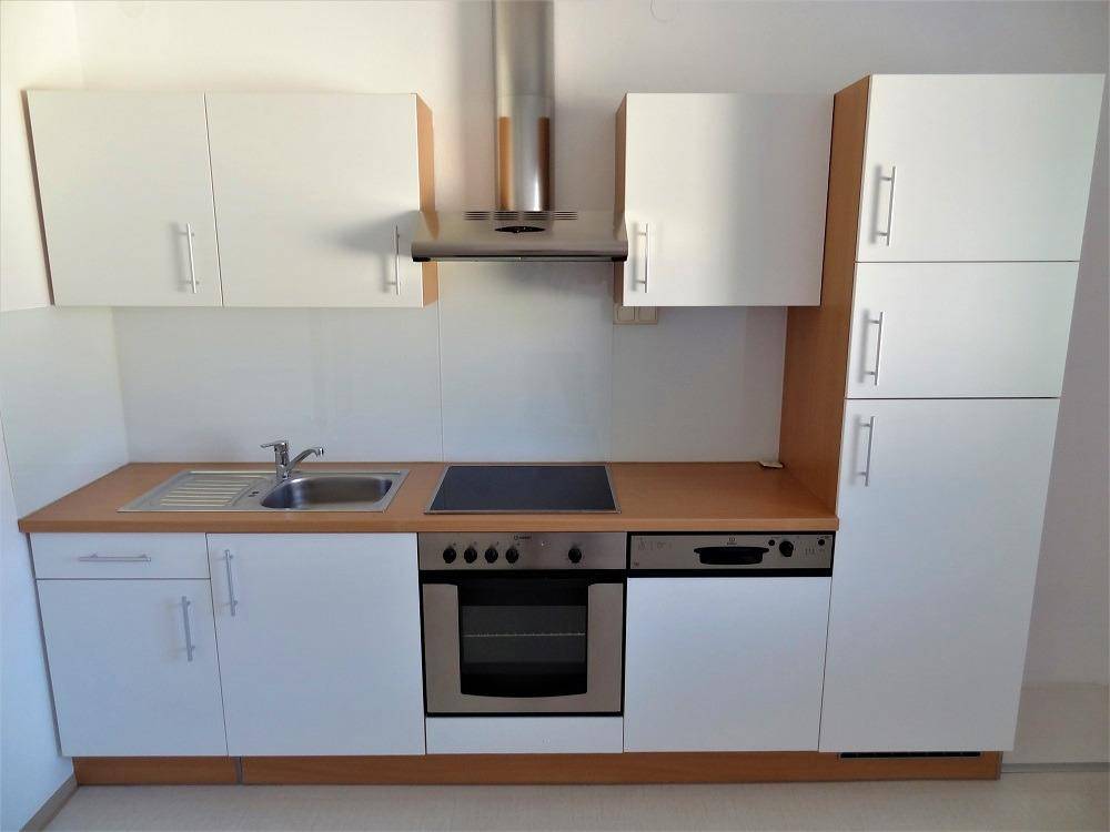 Gut erhaltene Einbauküche mit weißen Schränken, Holztheke und Edelstahlgeräten.