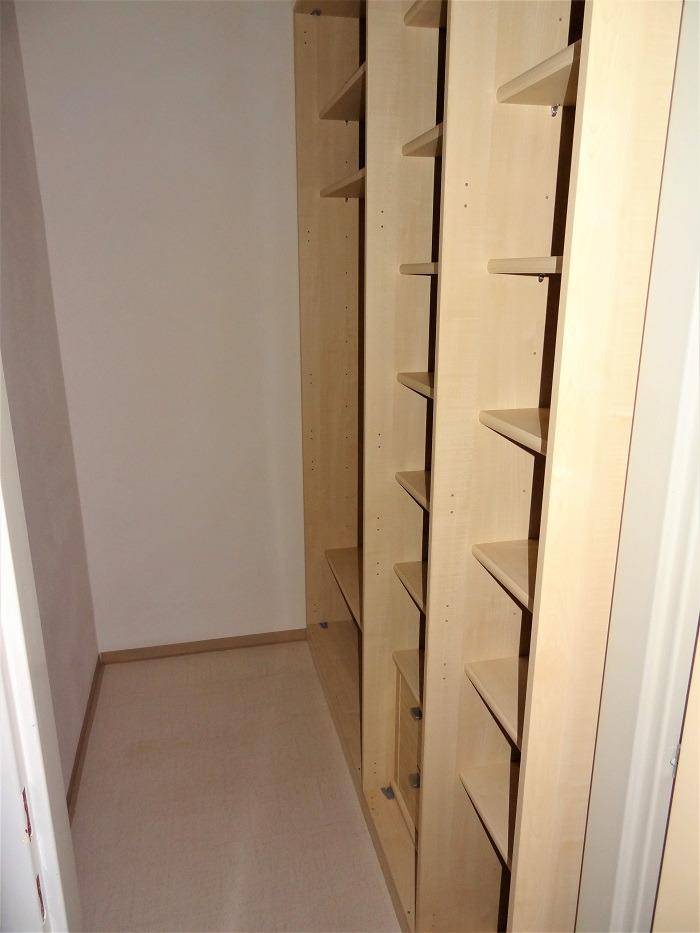 Begehbarer Schrank mit maßgefertigten Regalen und Schubladen für Kleidung und Accessoires.