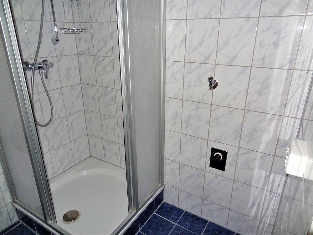 Duschbereich mit Glasabtrennung und hellen Fliesen im Badezimmer.