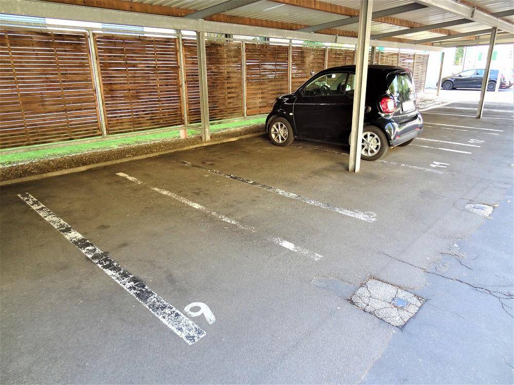 Überdachter Stellplatz in einem Carport mit einem geparkten Kleinwagen.