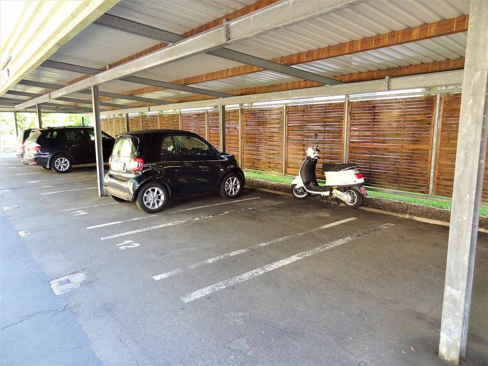 Ansicht der überdachten Parkplätze im Carport mit geparkten Fahrzeugen.