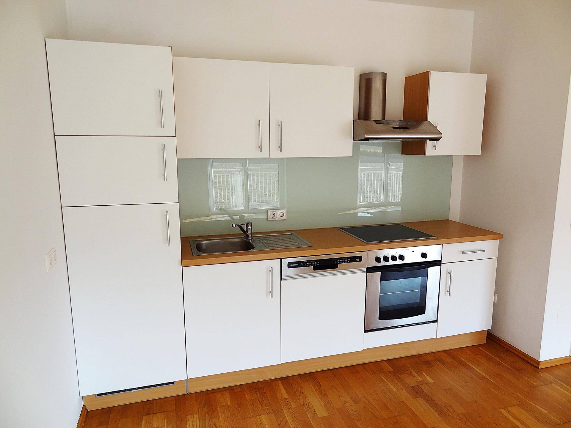 Funktionale Küche mit weißen Schränken, Holzdetails und Edelstahlgeräten, bietet ausreichend Stauraum und Arbeitsfläche.